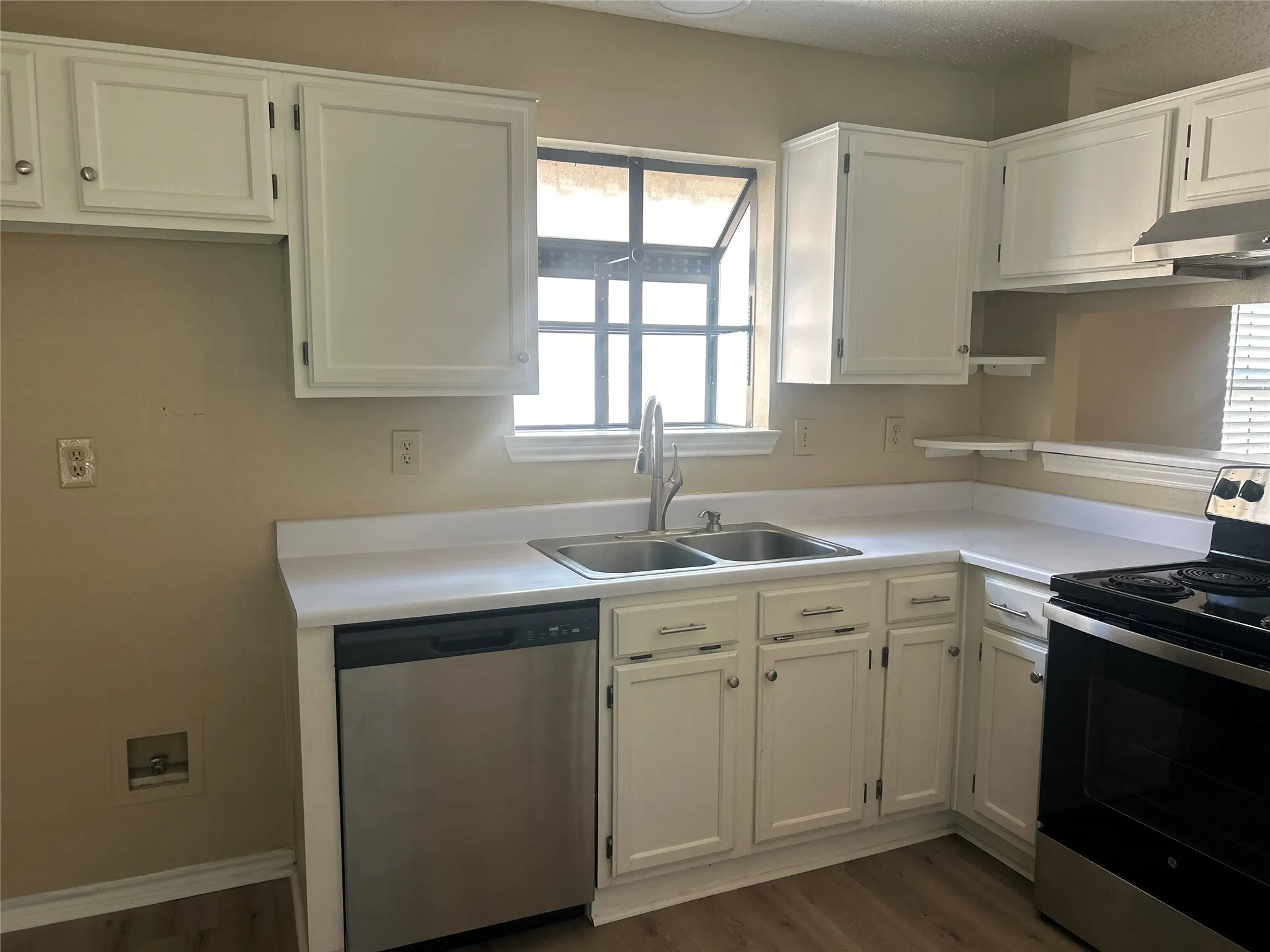 Kitchen featuring white cabinetry, dual basin sink with gooseneck faucet, stainless steel dishwasher, and a black and stainless steel range
