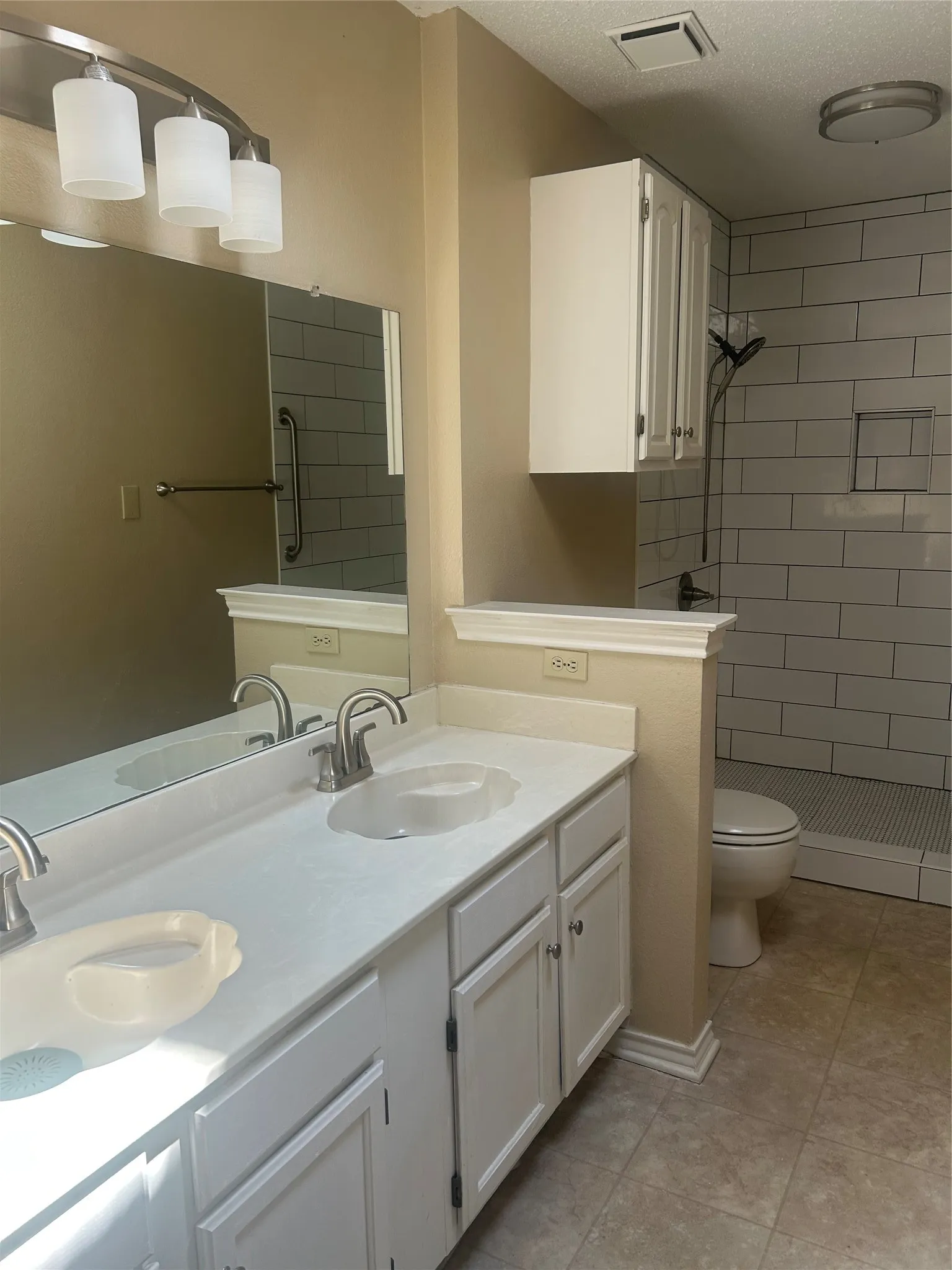 Dual vanity with integrated sinks, brushed nickel fixtures, white cabinetry, and large mirror