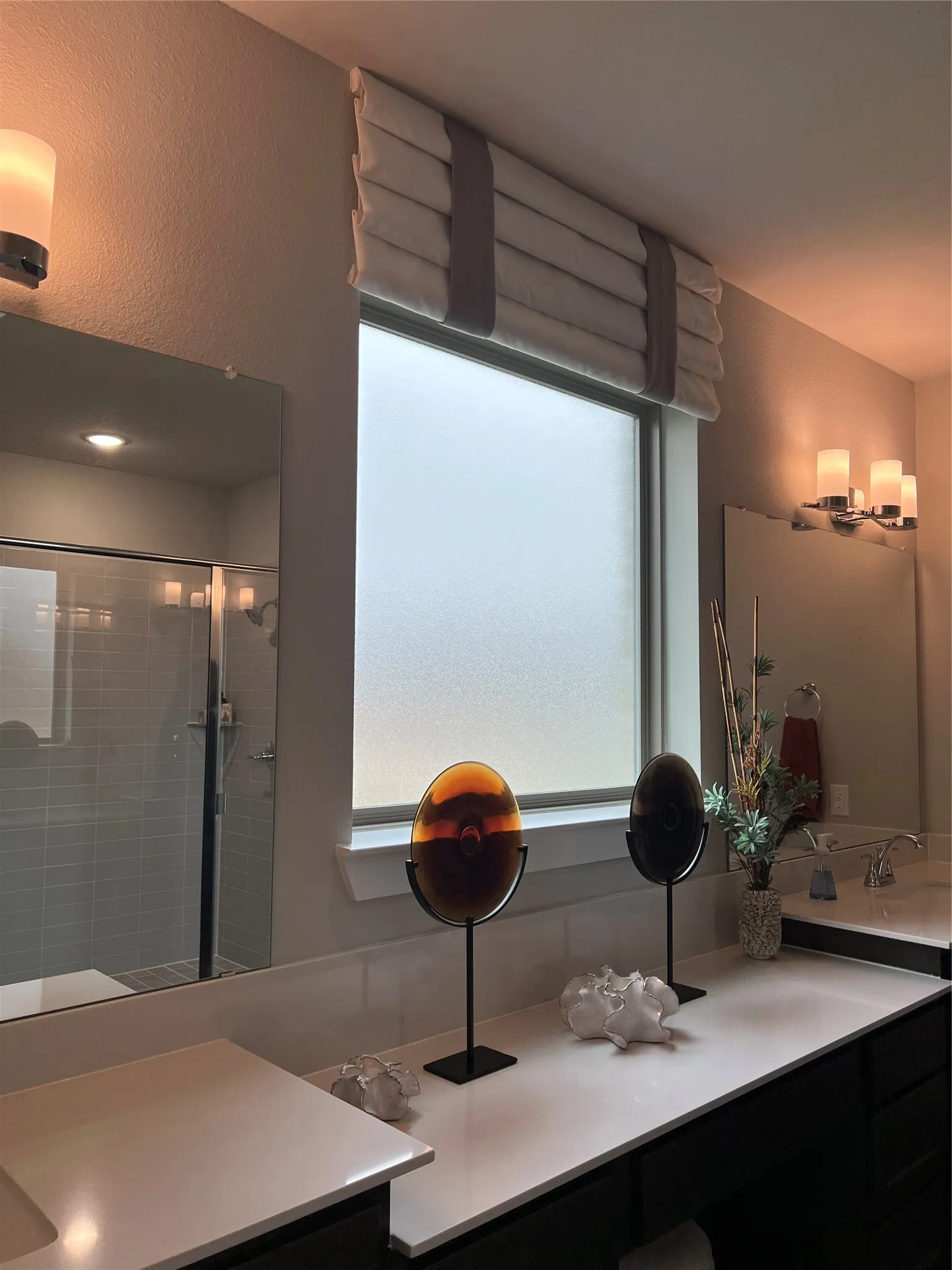 Spa-inspired primary bathroom featuring dual vanities with white quartz countertops, an expansive framed mirror, recessed lighting, and a walk-in shower with frameless glass enclosure and subway tile surround