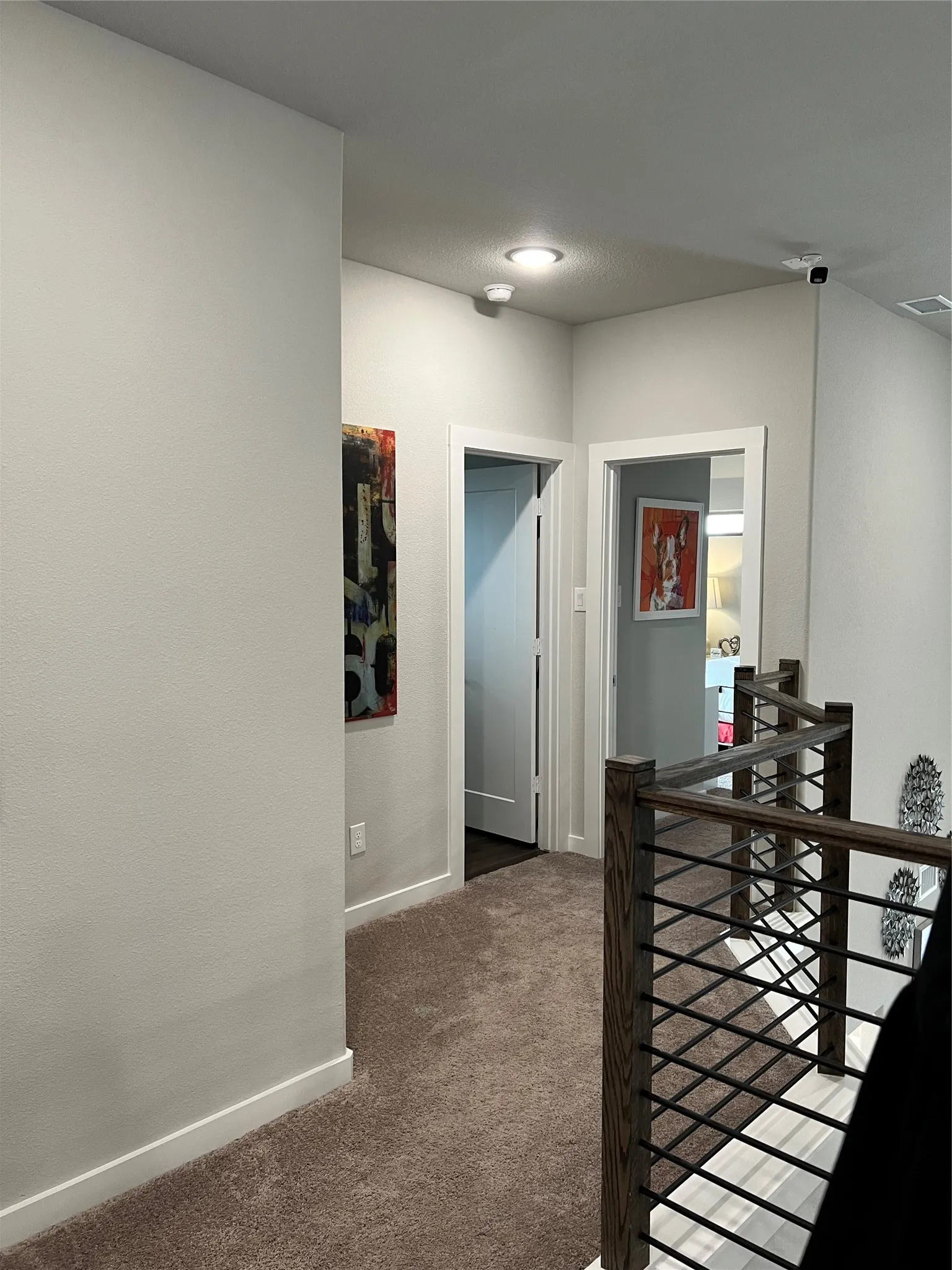 Carpeted hallway featuring recessed lighting and a wood-finish and metal baluster railing