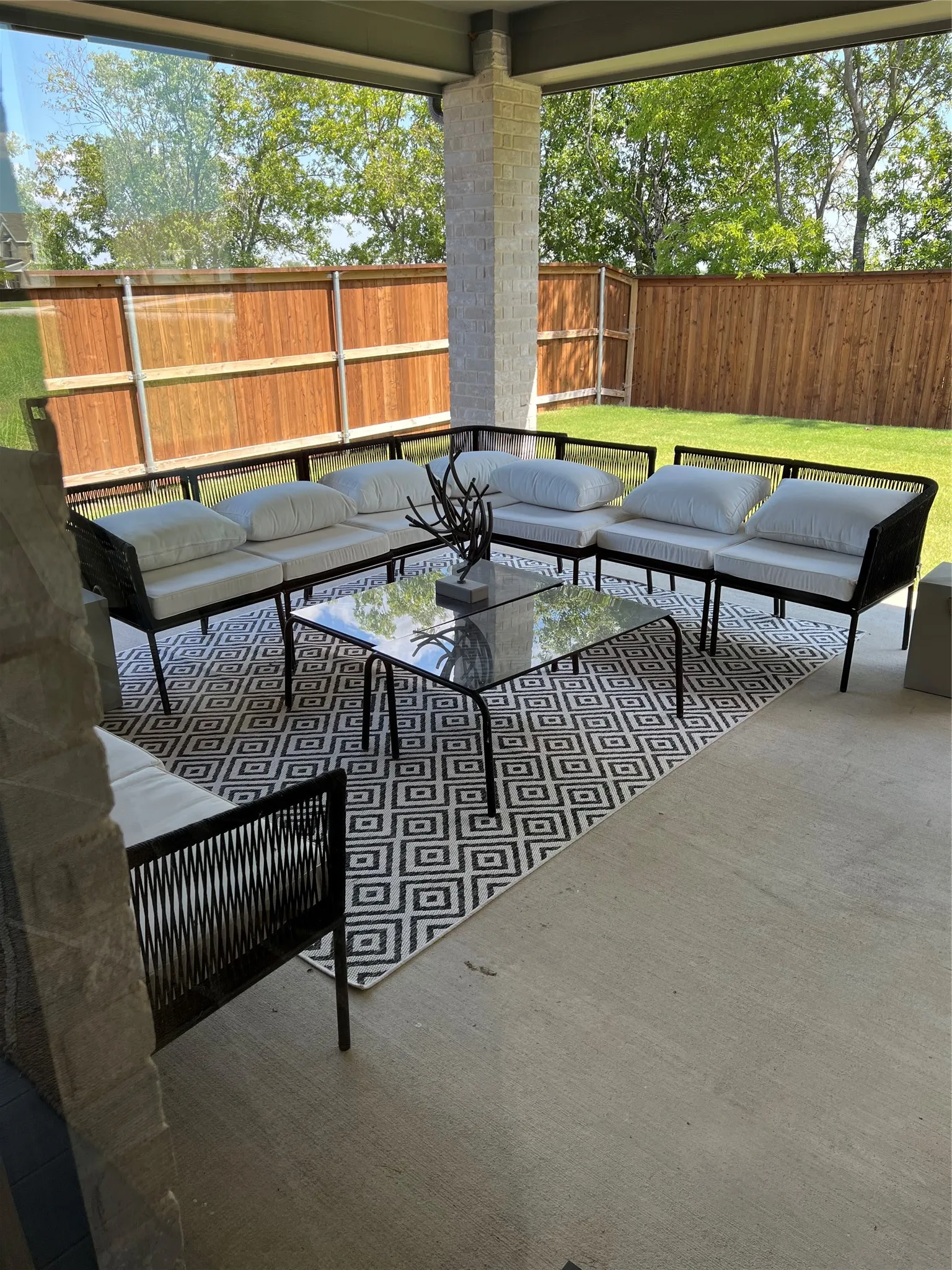 Covered patio with a stone column, concrete flooring, and a fenced backyard