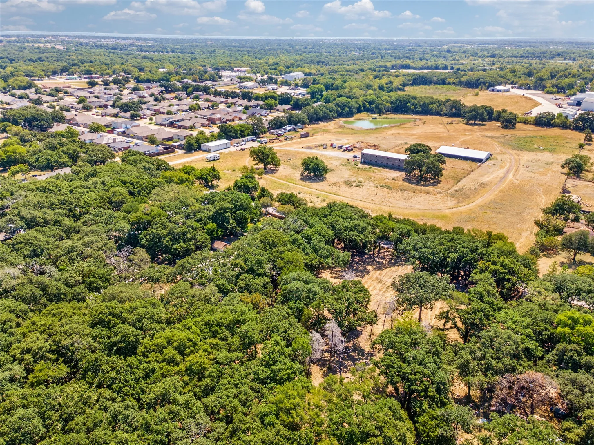 Expansive property featuring dense tree coverage, open land, and multiple outbuildings