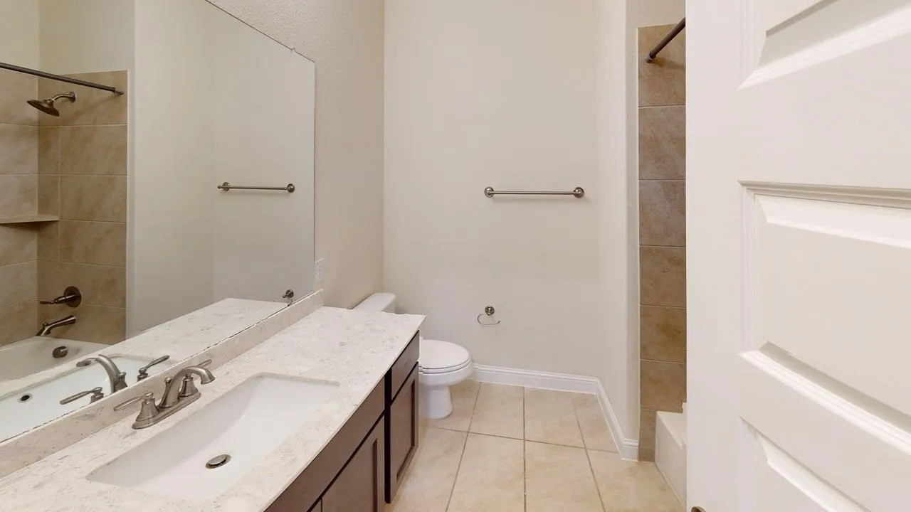 Dual vanity with marble-finish countertops and brushed nickel fixtures, ceramic tile flooring, and abundant natural lighting