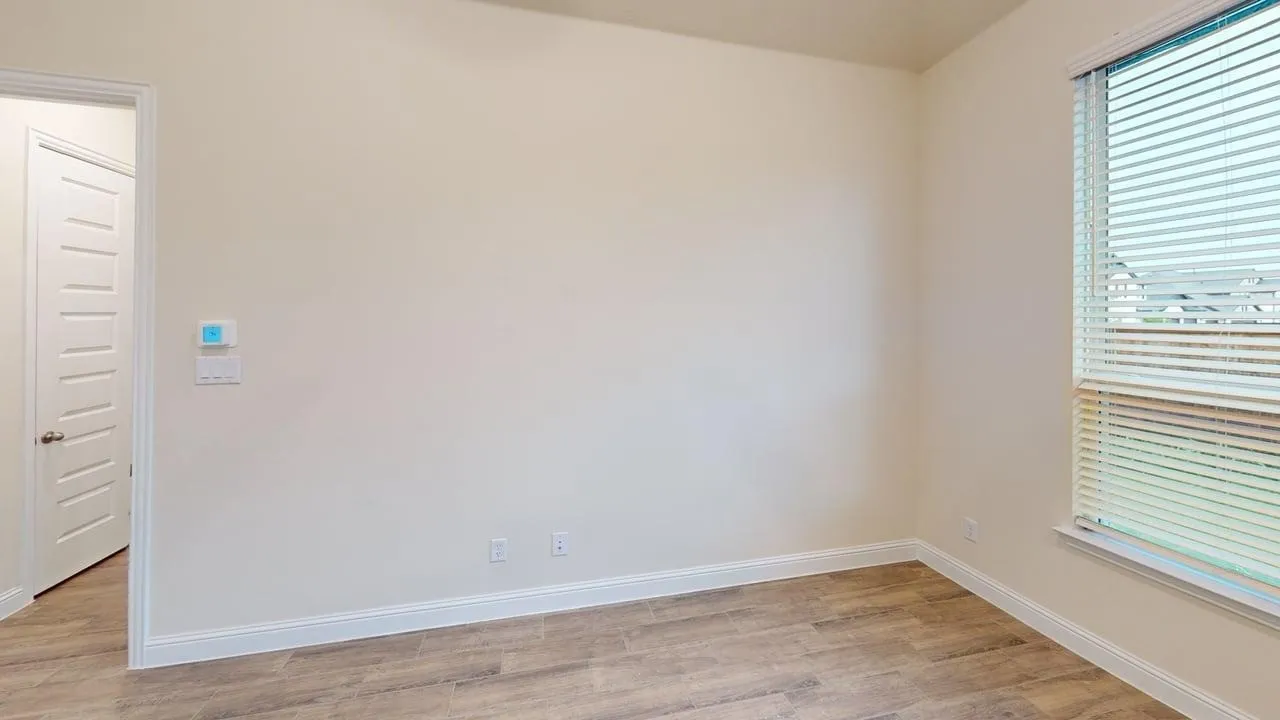 Wood-finish flooring with white trim and a window with blinds