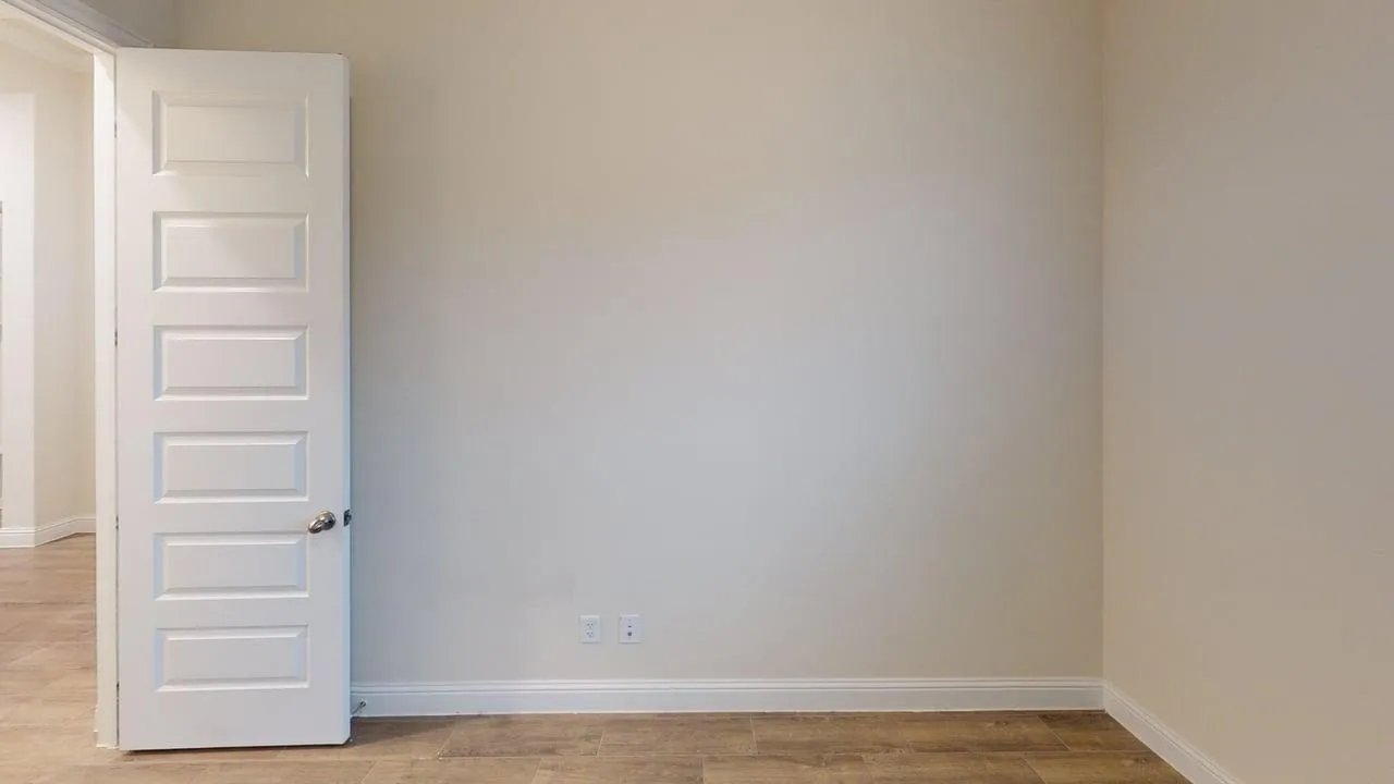 Wood-finish flooring, light-colored wall paint, white trim, and a five-panel interior door