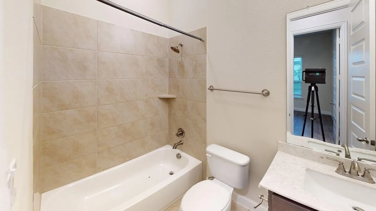 Bathtub with tiled surround, wall-mounted shower head, and built-in shelf