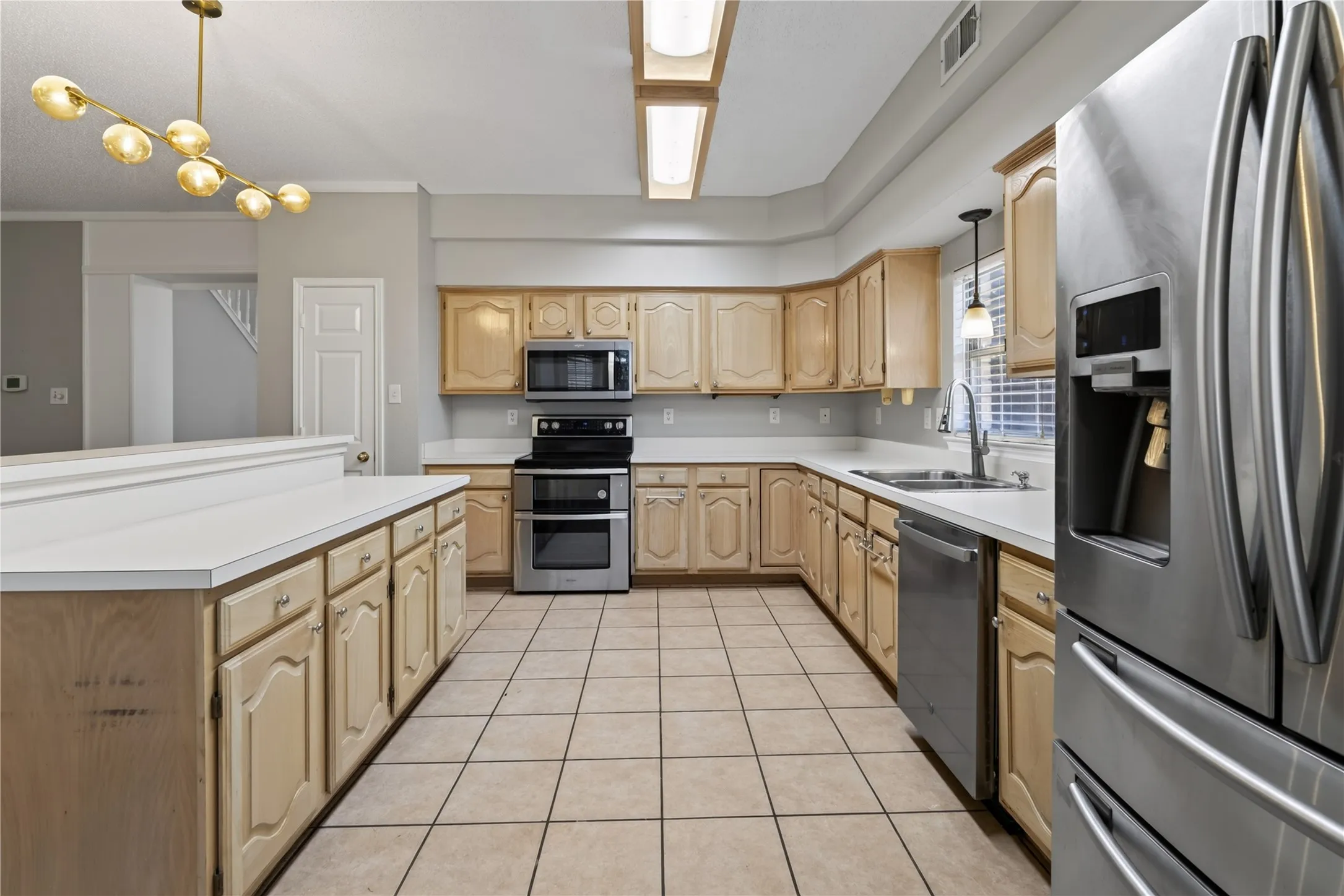 Kitchen featuring wood cabinetry, white countertops, tile flooring, and stainless steel appliances