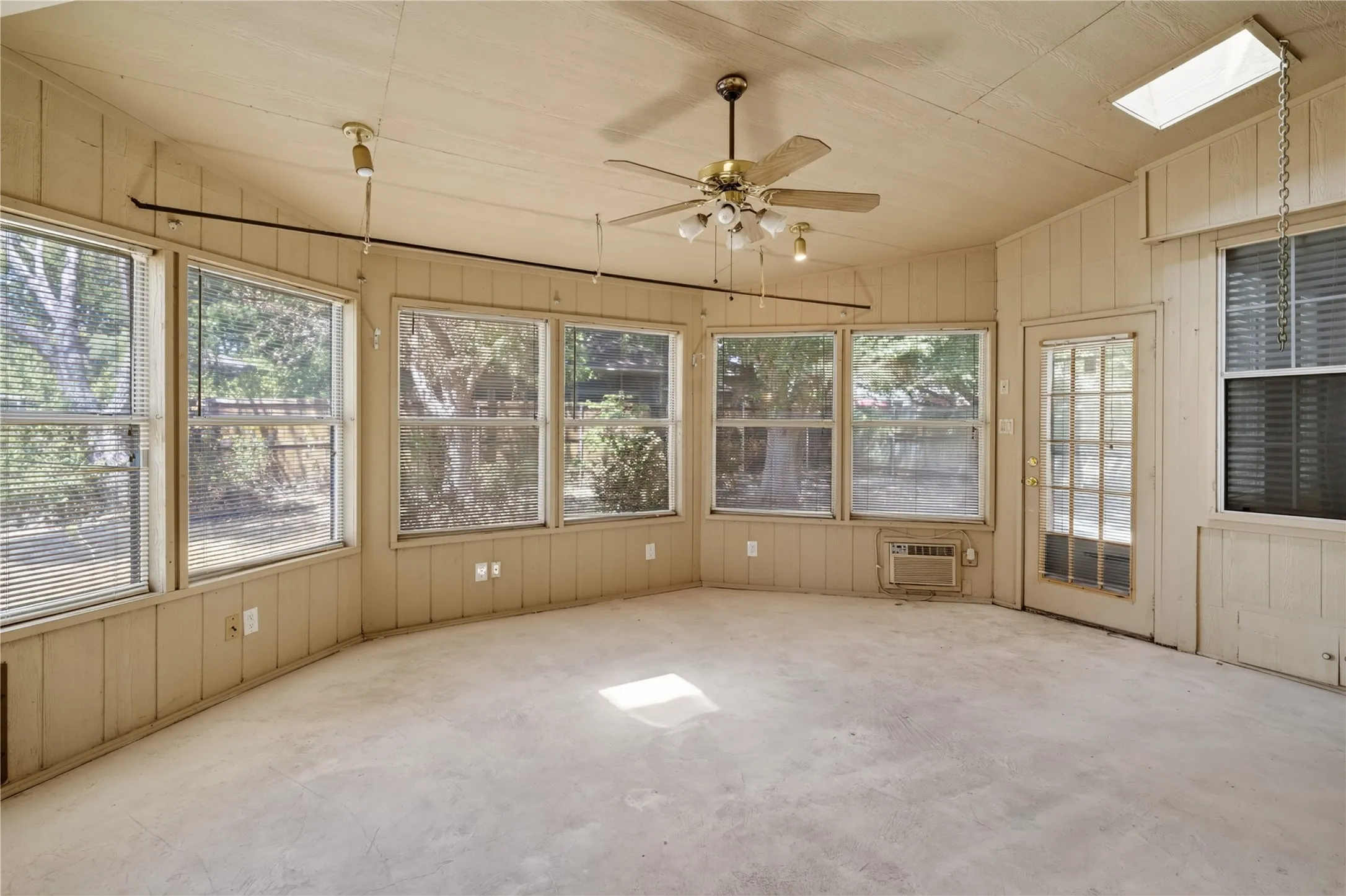 Sunroom with multiple windows, a ceiling fan, and a skylight