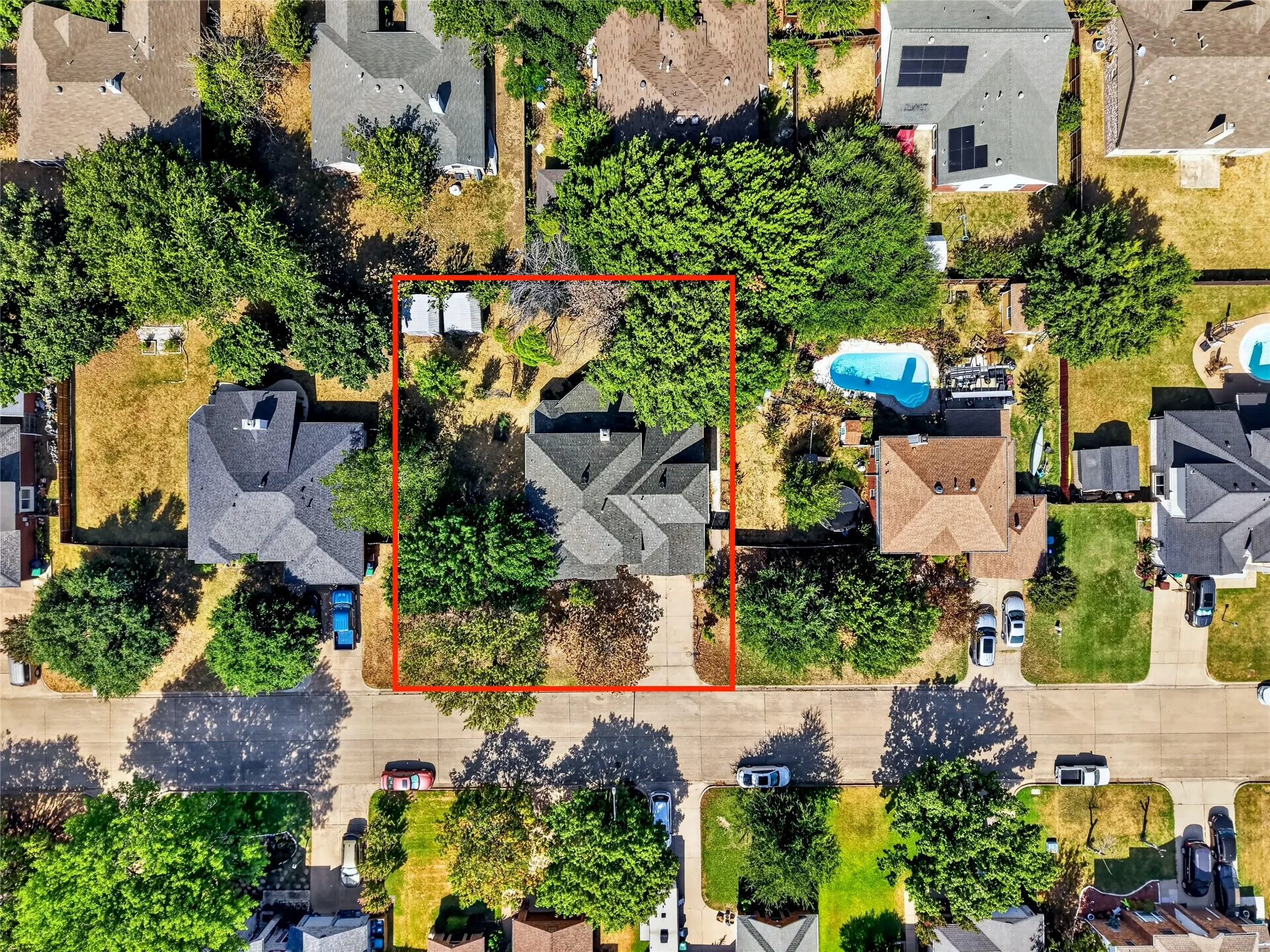 Property with a grey shingled roof, mature trees, and a concrete driveway