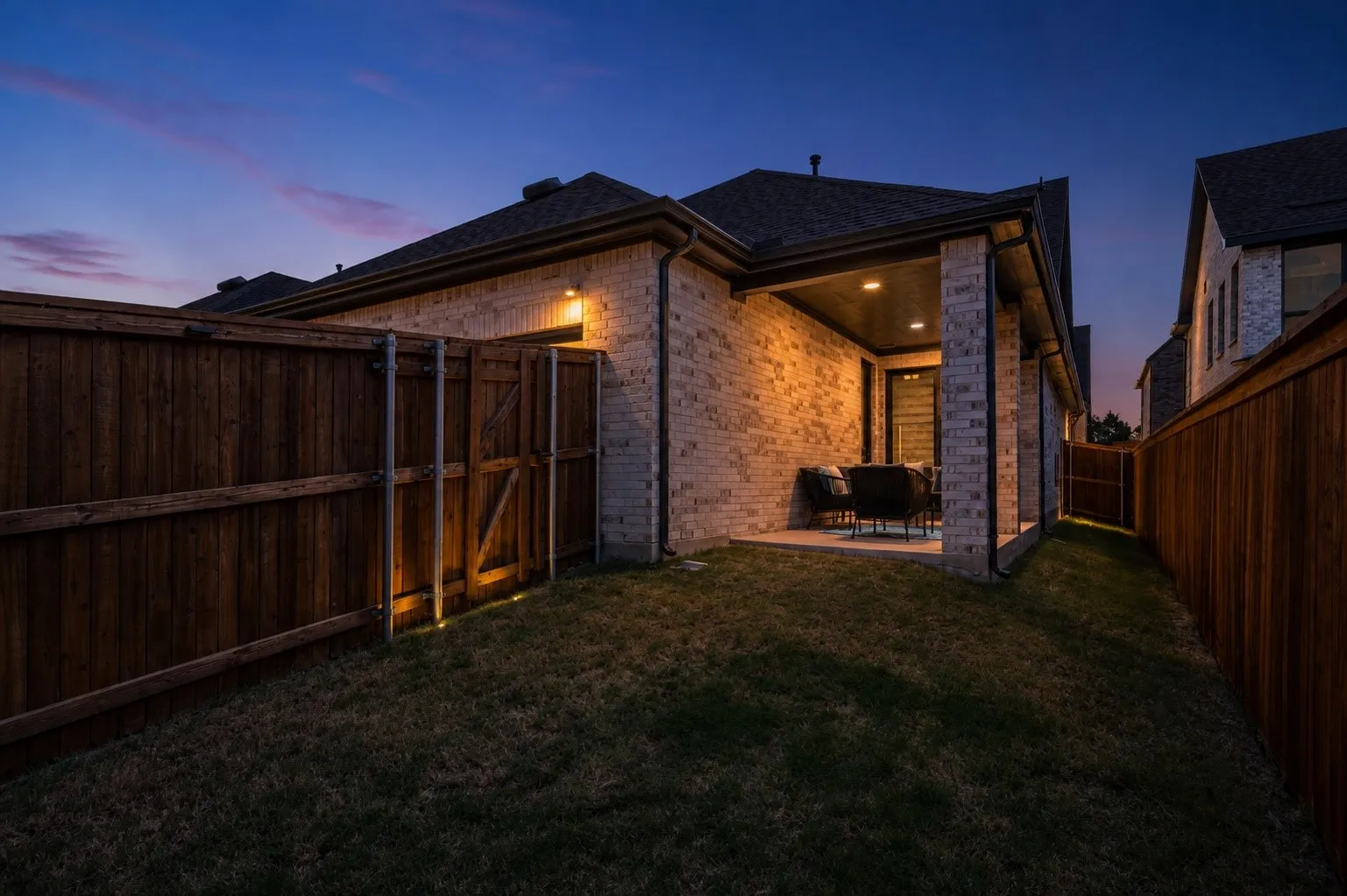Brick exterior with a covered patio, recessed lighting, and a wood privacy fence