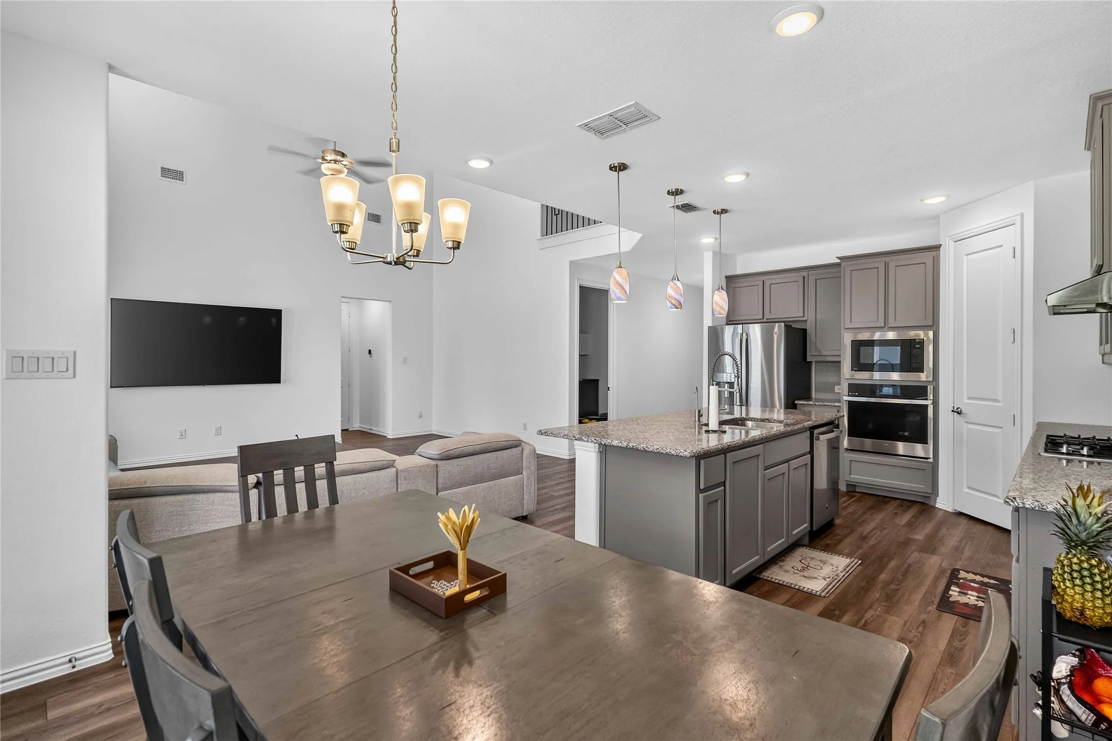 Open-concept living space featuring wood-finish flooring, vaulted ceilings, and recessed lighting