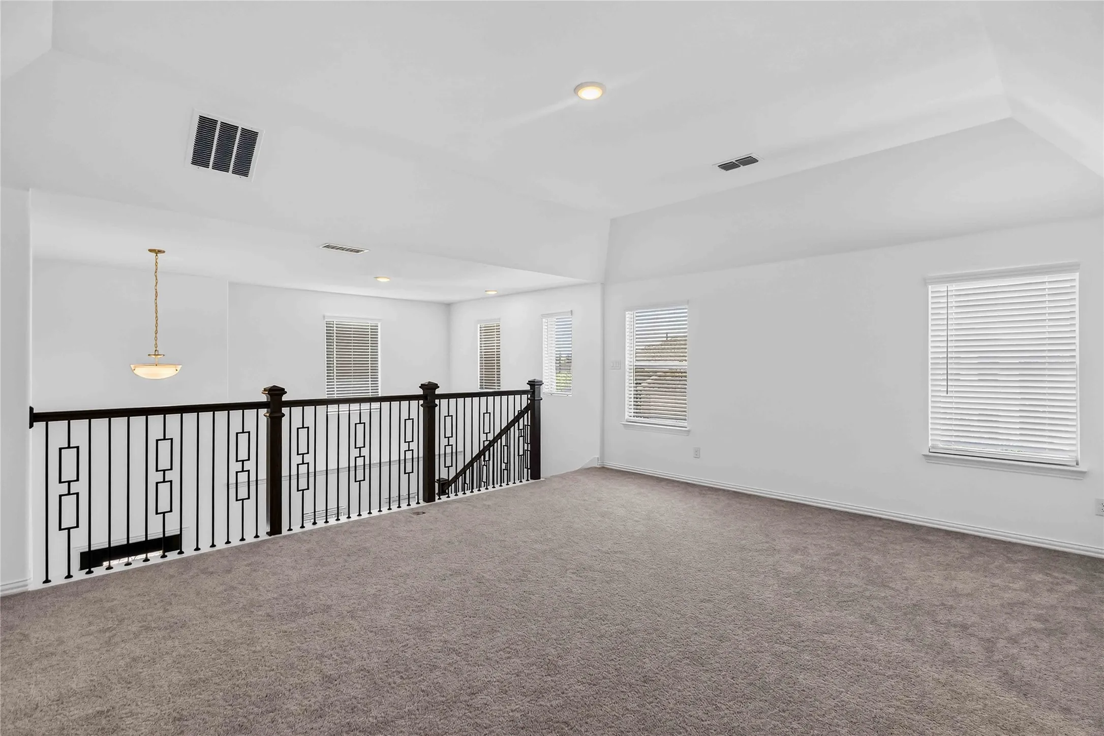 Spacious loft-style room featuring soaring ceilings with recessed lighting, expansive carpet flooring, and abundant natural light from multiple windows with plantation shutters