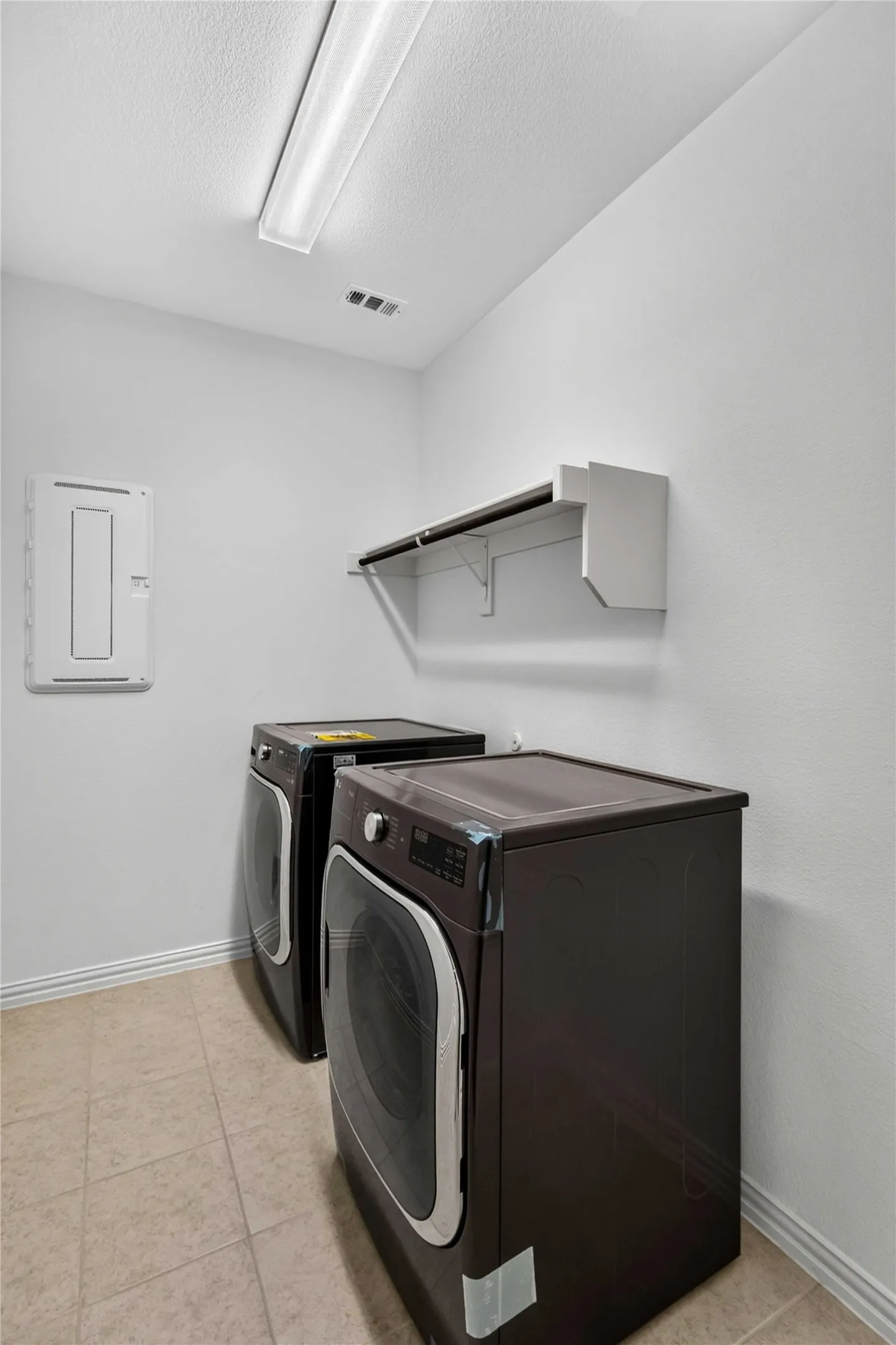 Dedicated laundry room featuring side-by-side capacity with front-load washers and dryers, wall-mounted drying rack, recessed lighting, and light wood-finish flooring throughout