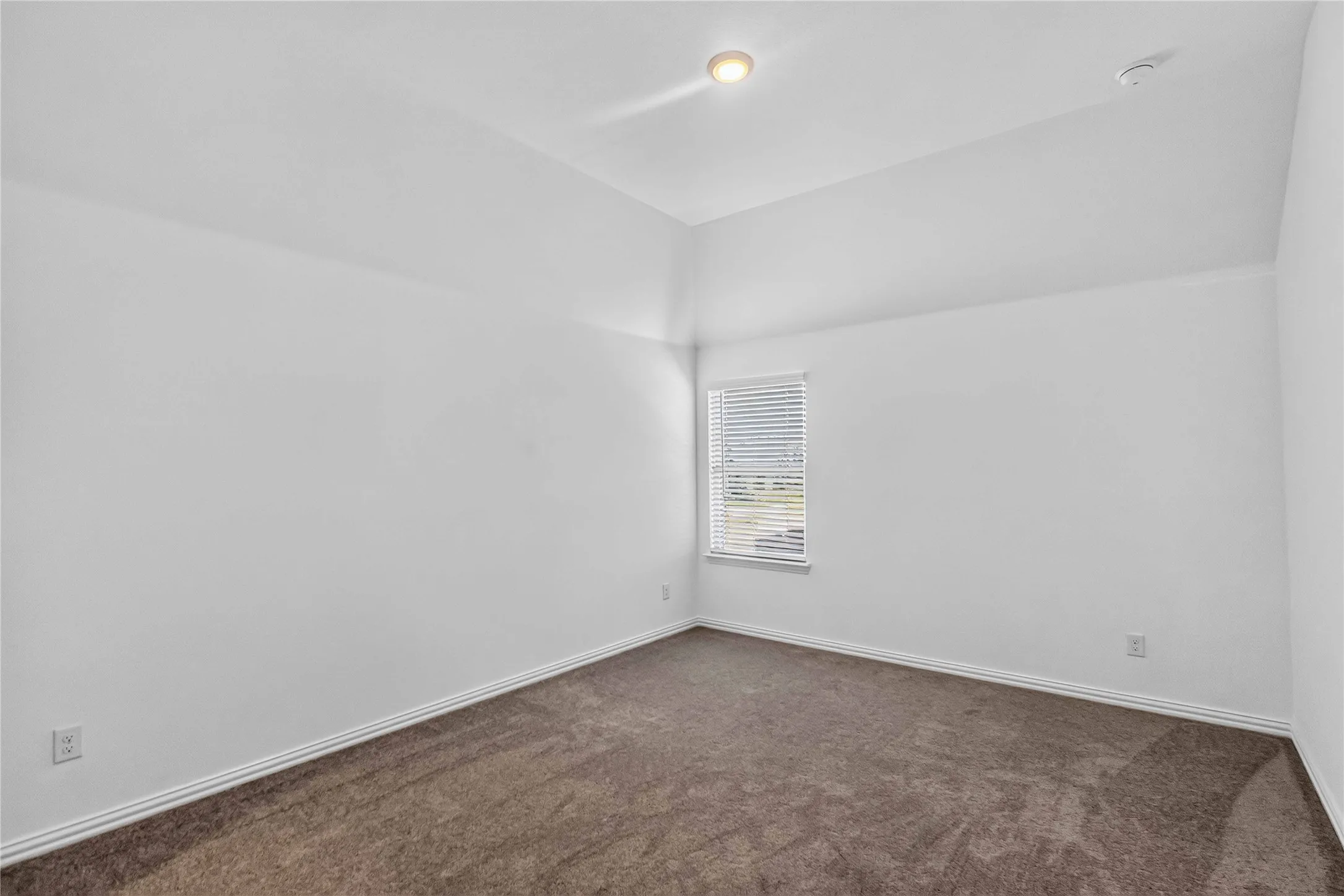 Bright corner bedroom featuring pristine white walls, recessed ceiling lighting, and warm wood-finish flooring
