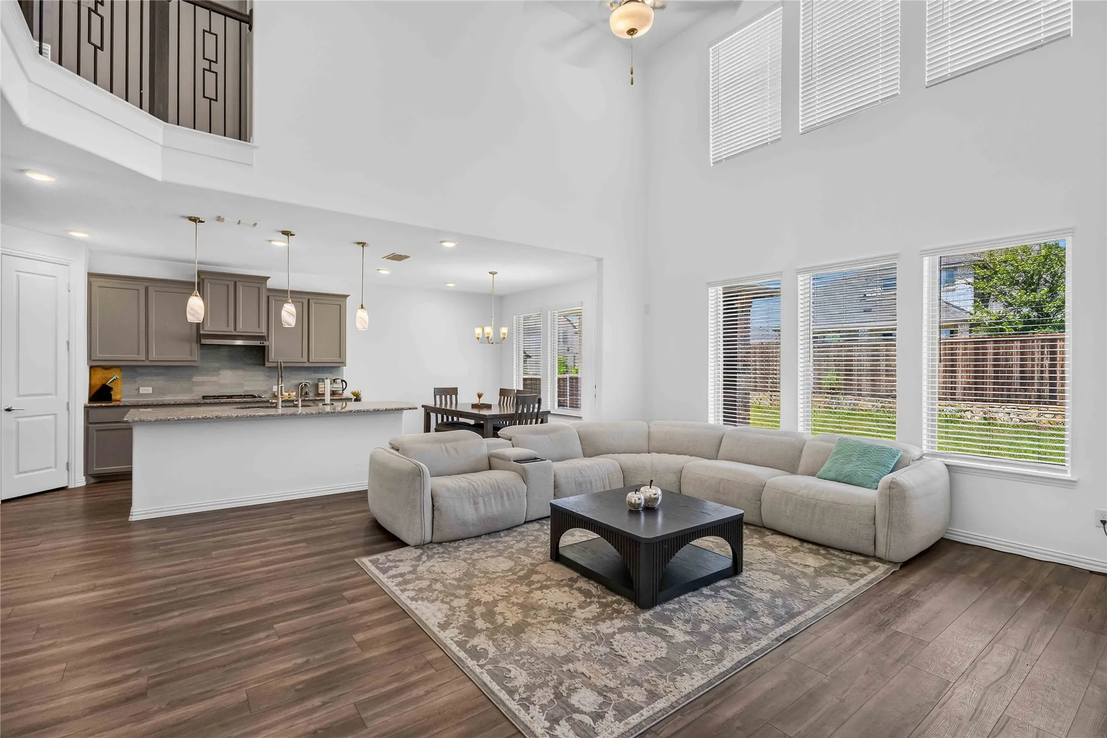 Two-story living area with high ceilings, wood-finish flooring, and multiple windows