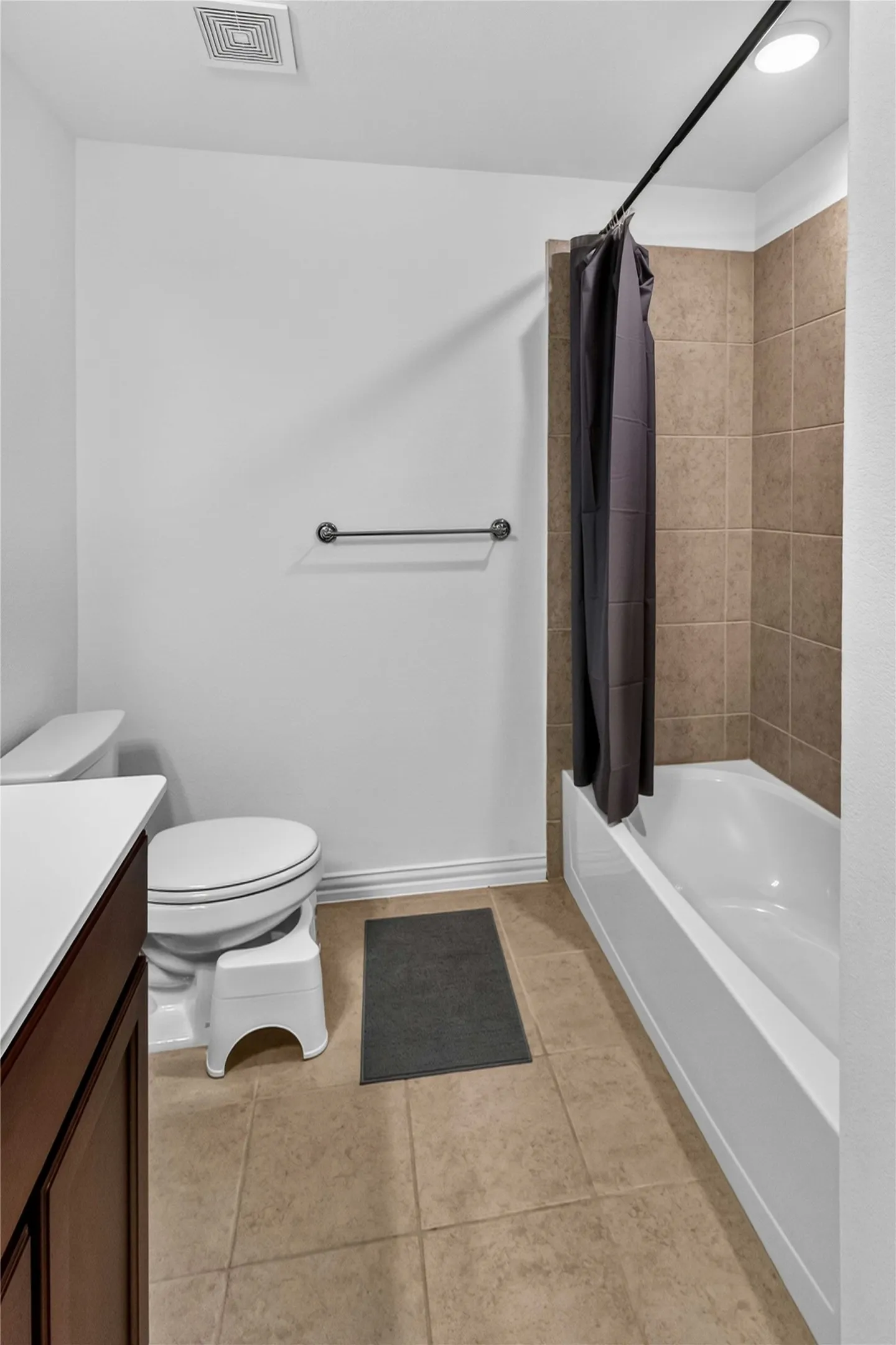 Bathroom with a white bathtub, tiled shower surround, recessed lighting, and a dark wood-finish vanity with a white countertop