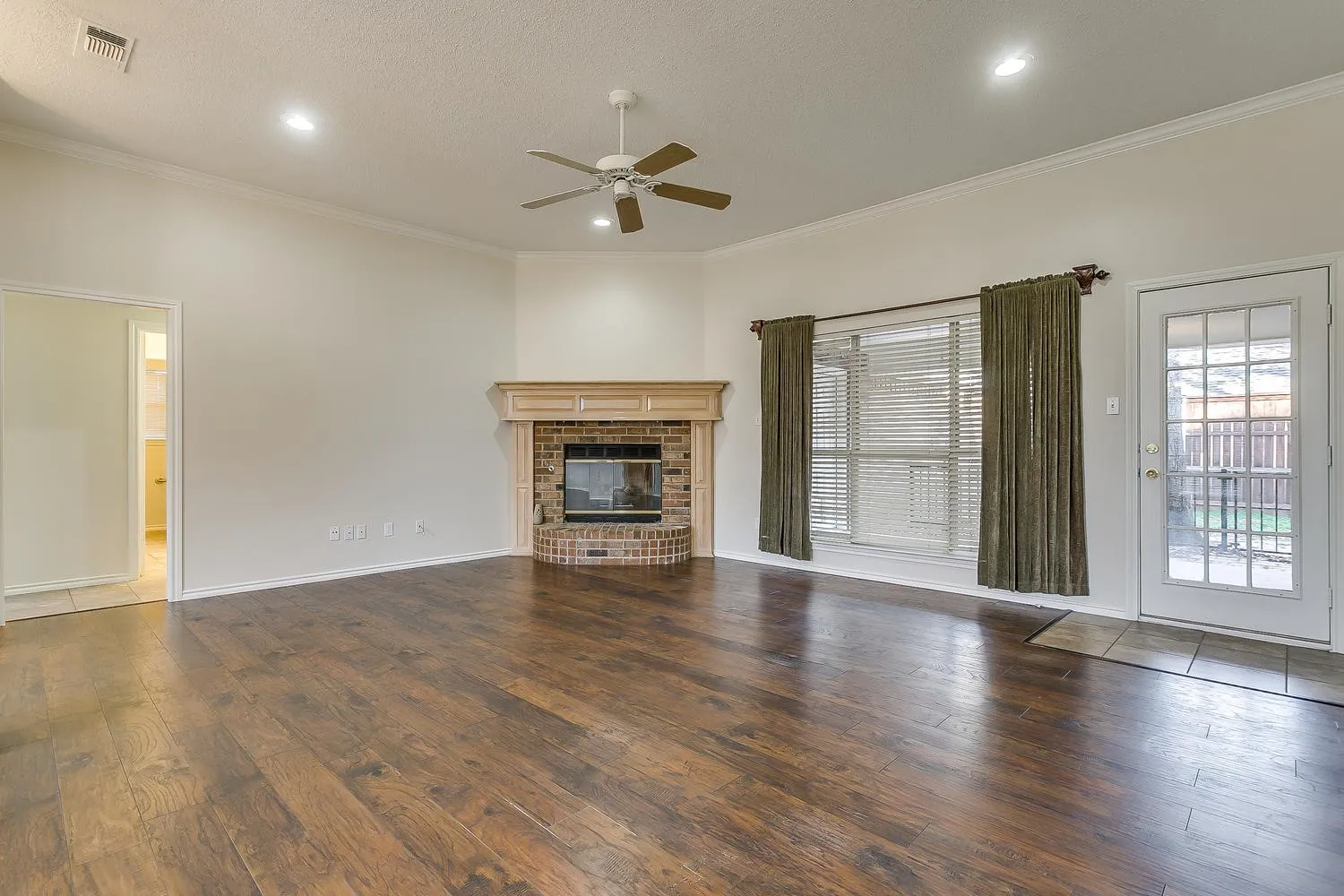 Spacious living area featuring wood-finish flooring, a brick fireplace with a wood mantle, a ceiling fan, and recessed lighting