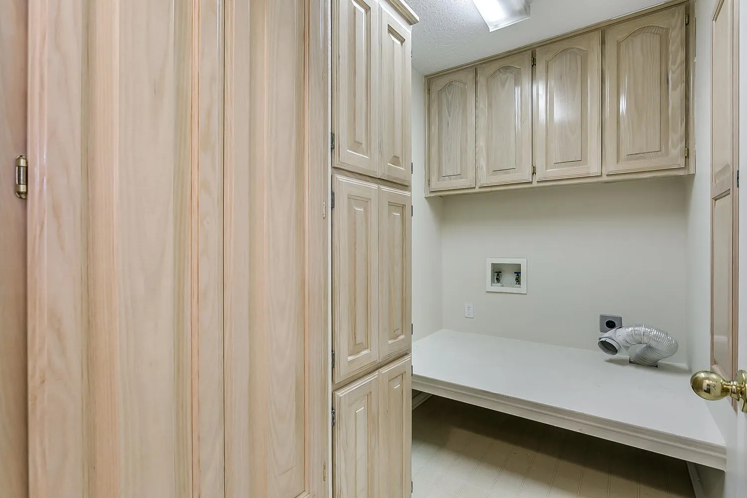 Spacious built-in closet system featuring light wood-finish cabinetry with recessed panel doors, integrated shelving, and ample storage capacity
