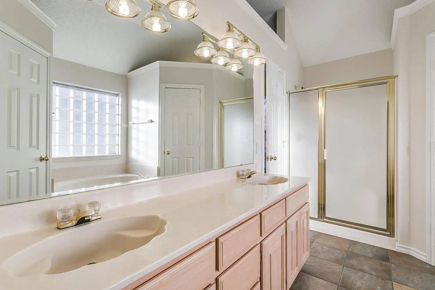 Spa-inspired primary bathroom featuring dual vanities with wood-finish cabinetry, expansive quartz countertops, and an undermount sink
