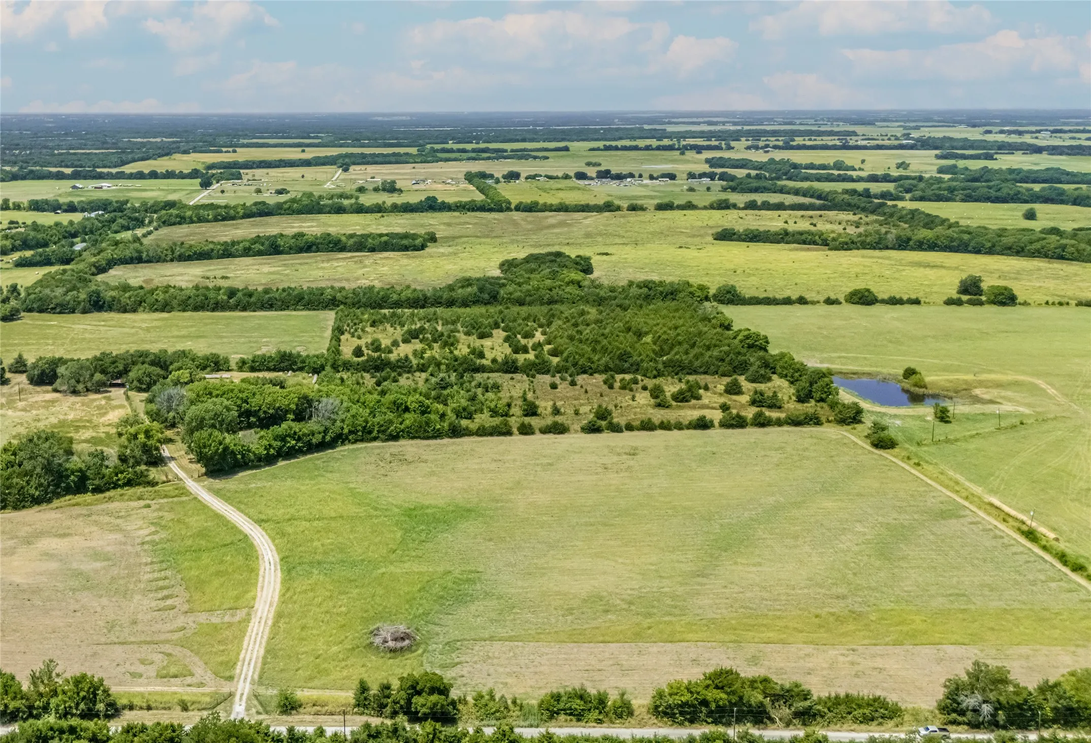 Expansive acreage featuring open fields, clusters of mature trees.