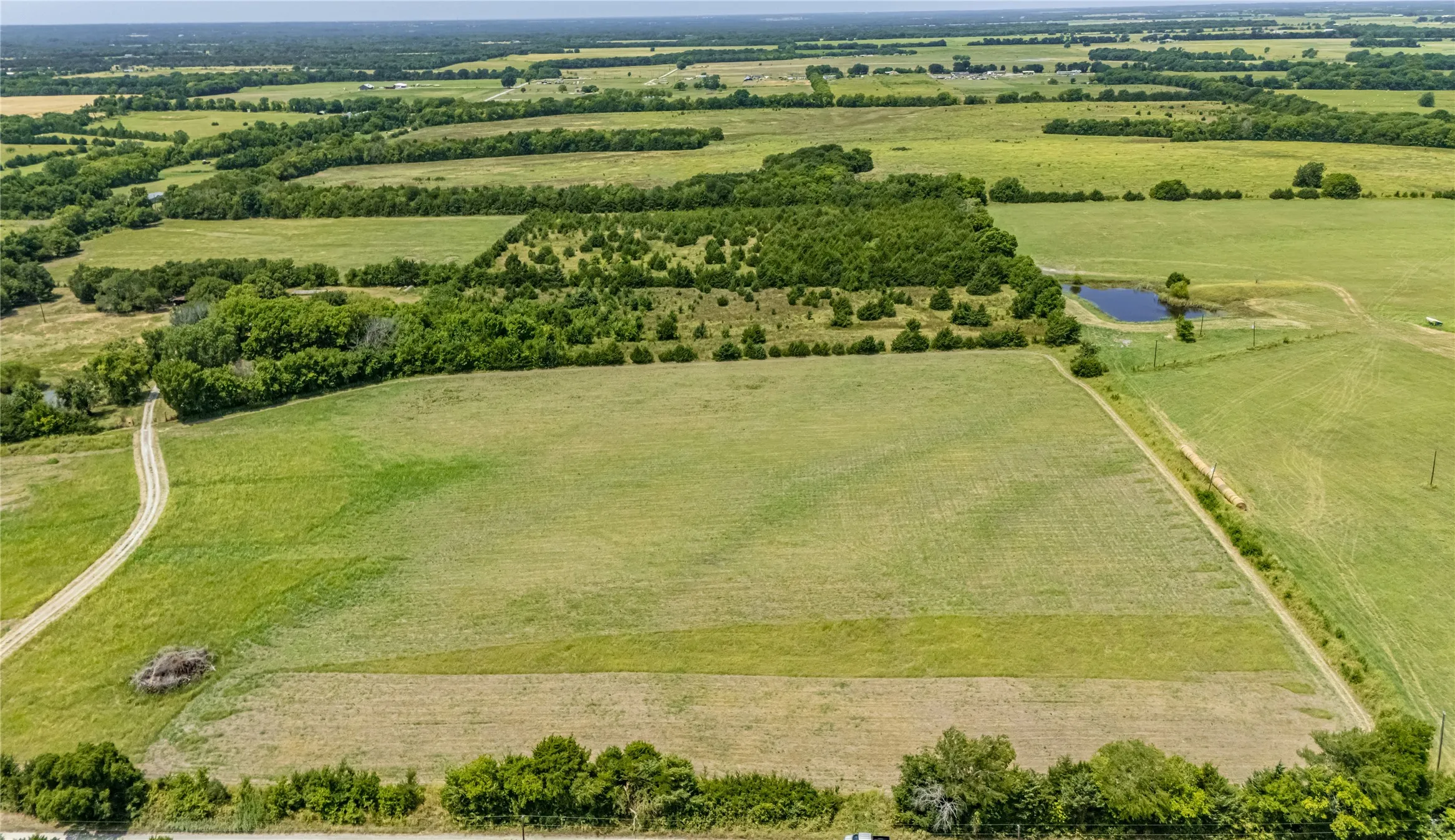 Expansive agricultural property featuring multiple cleared pastures with mature tree lines, gently rolling terrain