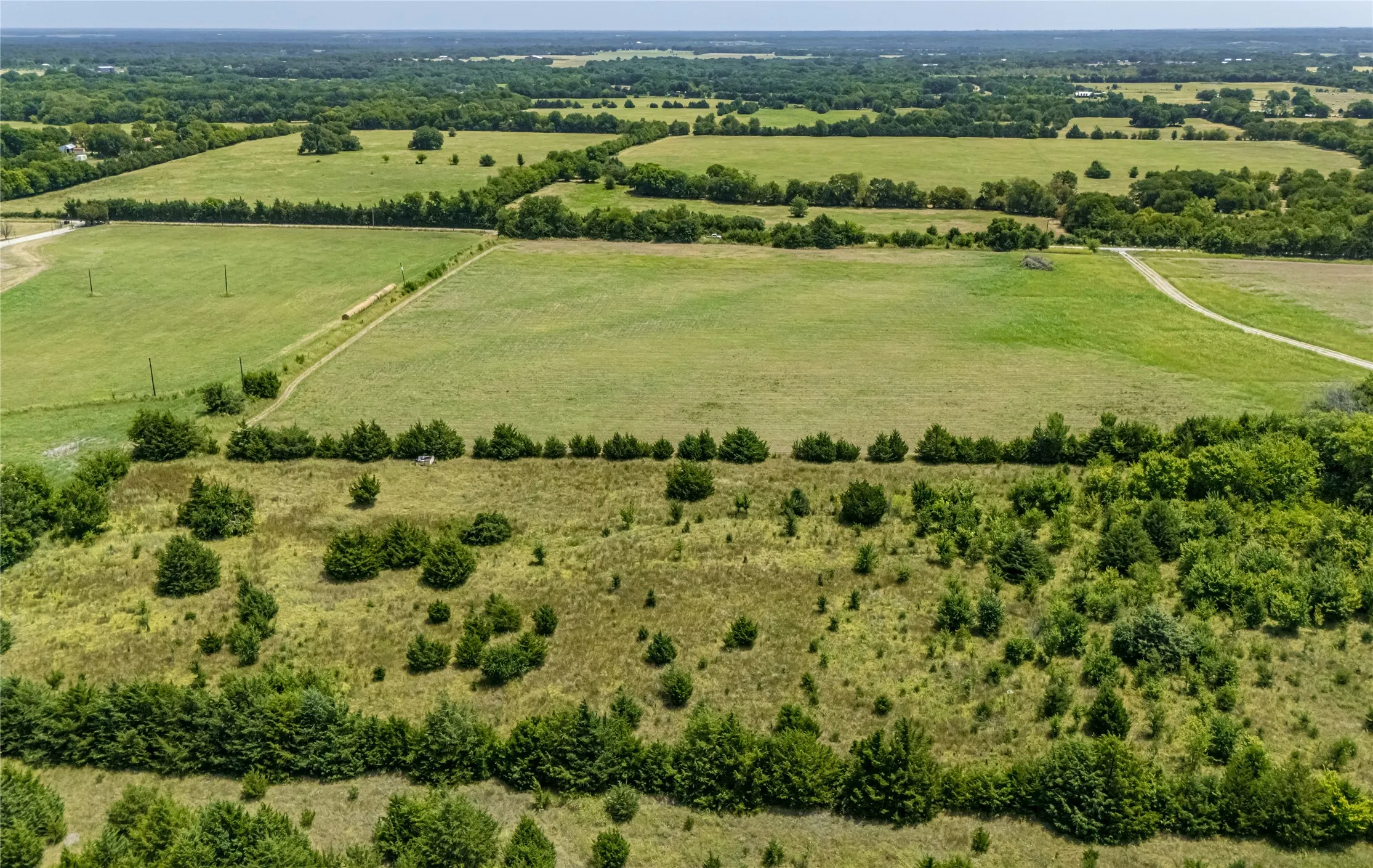 Expansive land featuring open fields, diverse vegetation, and natural tree lines