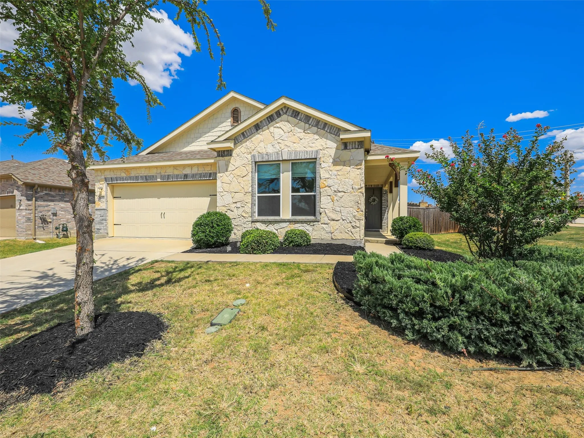 Another view of the home’s charming exterior, highlighted by stonework, mature landscaping, and a covered front entry.