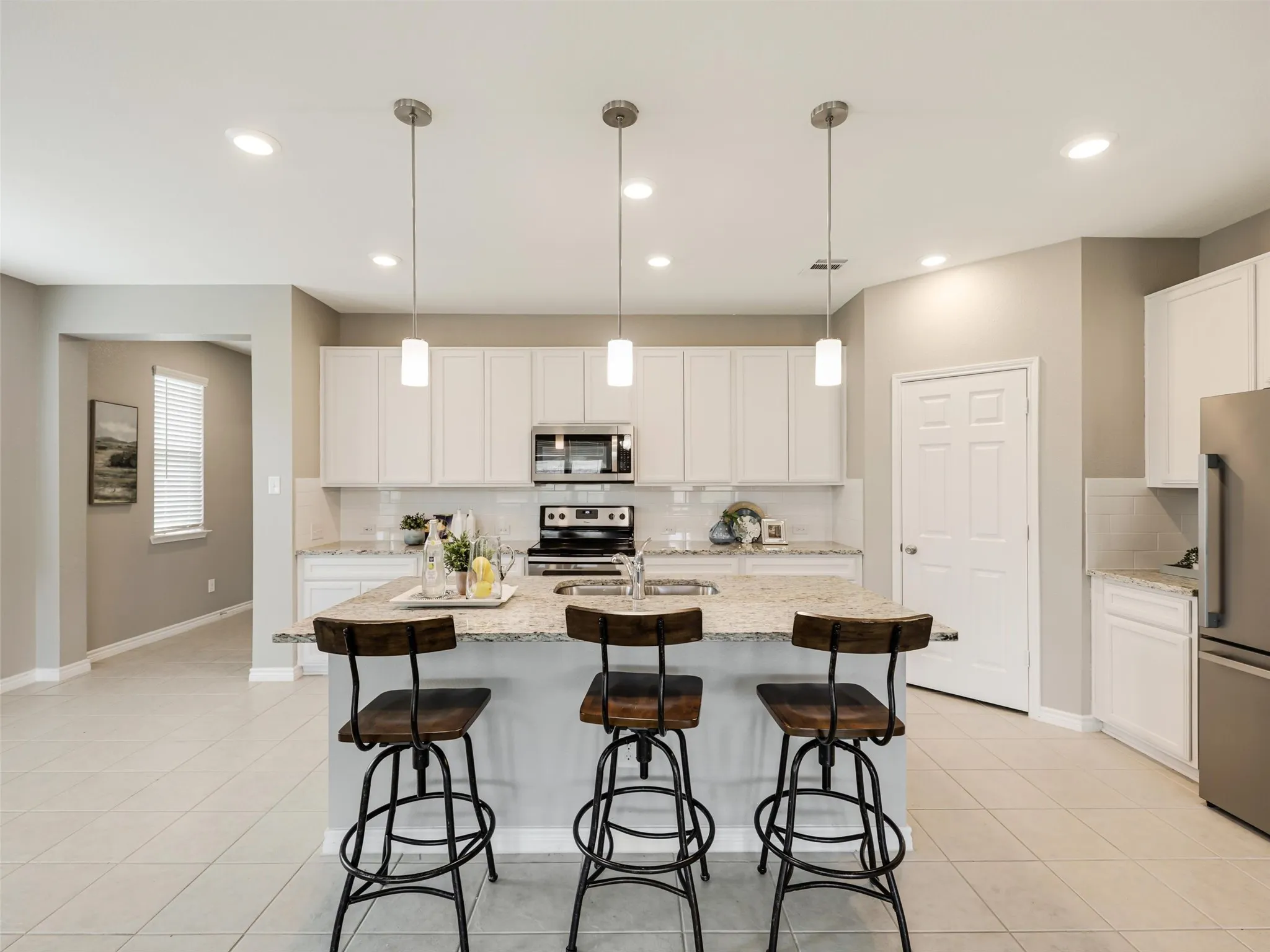 The oversized kitchen island provides additional workspace and comfortable seating, creating the perfect gathering place for meals, homework, or conversation.