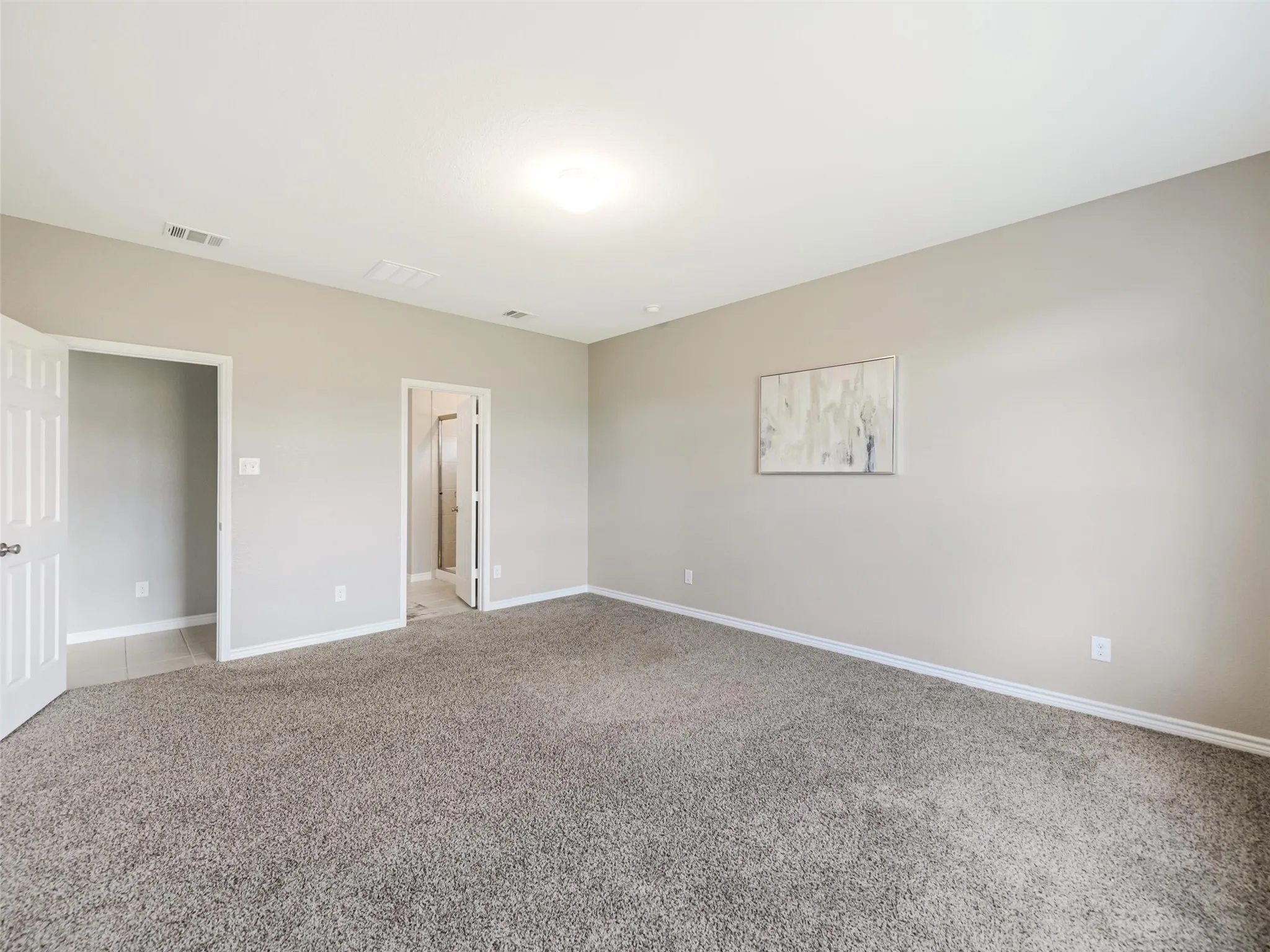 The generously sized primary suite offers plenty of flexibility for a complete bedroom arrangement and provides convenient access to the private bathroom.