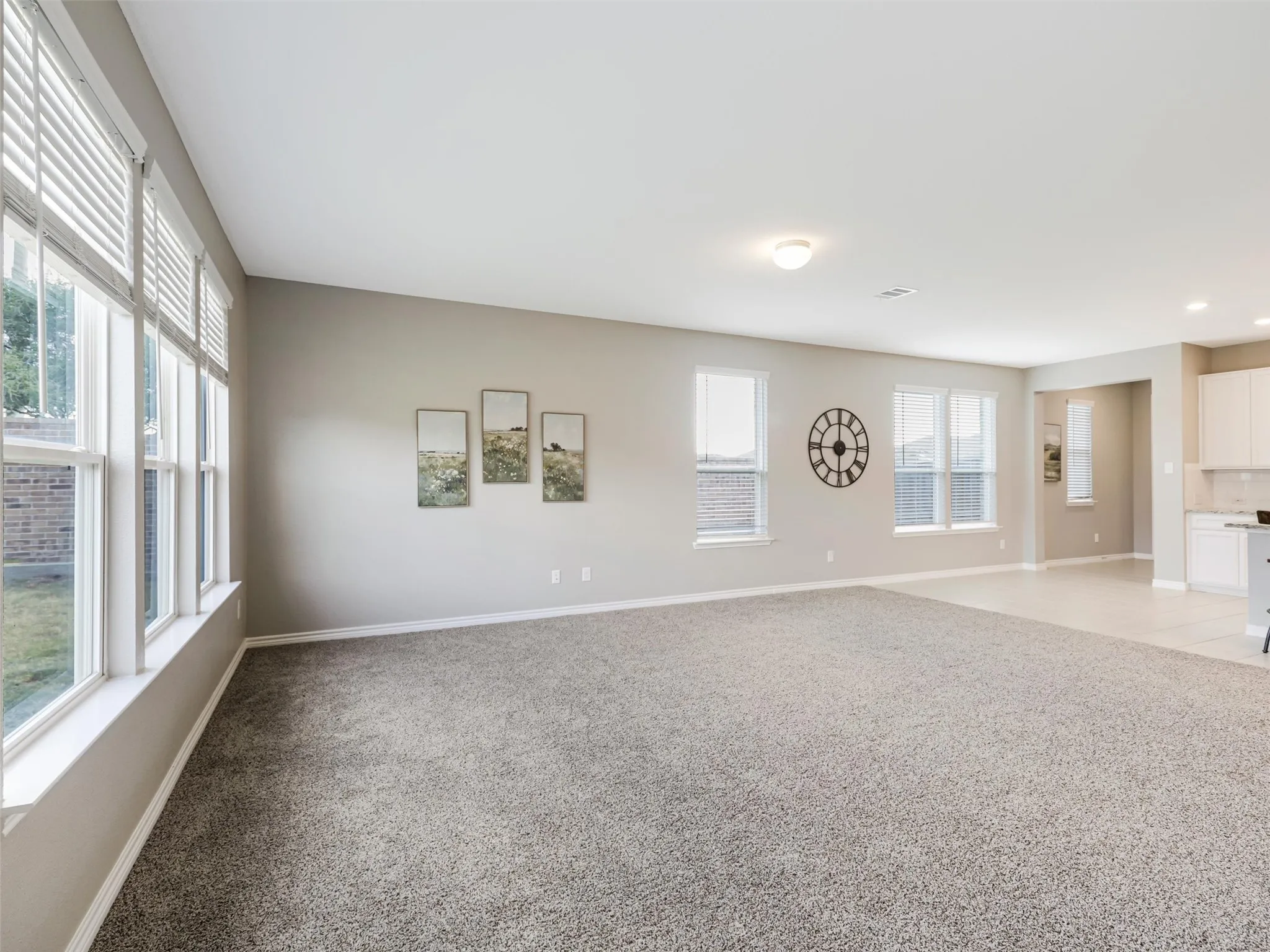 Generously sized living room features neutral finishes, plush carpeting, and multiple windows that bring in abundant natural light.