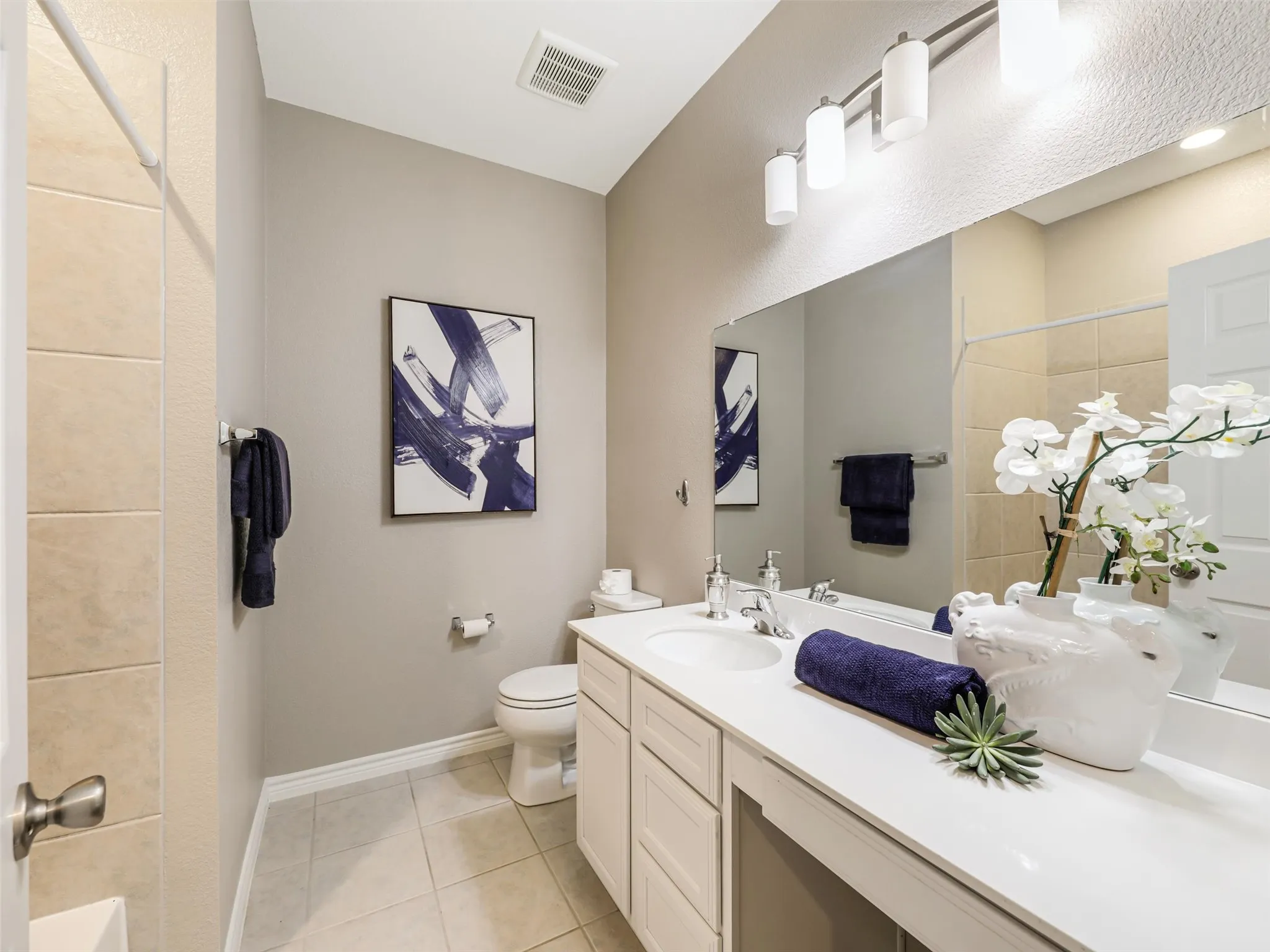 Full secondary bathroom features a spacious vanity, generous counter space, an oversized mirror, modern lighting, and a tub-shower combination.