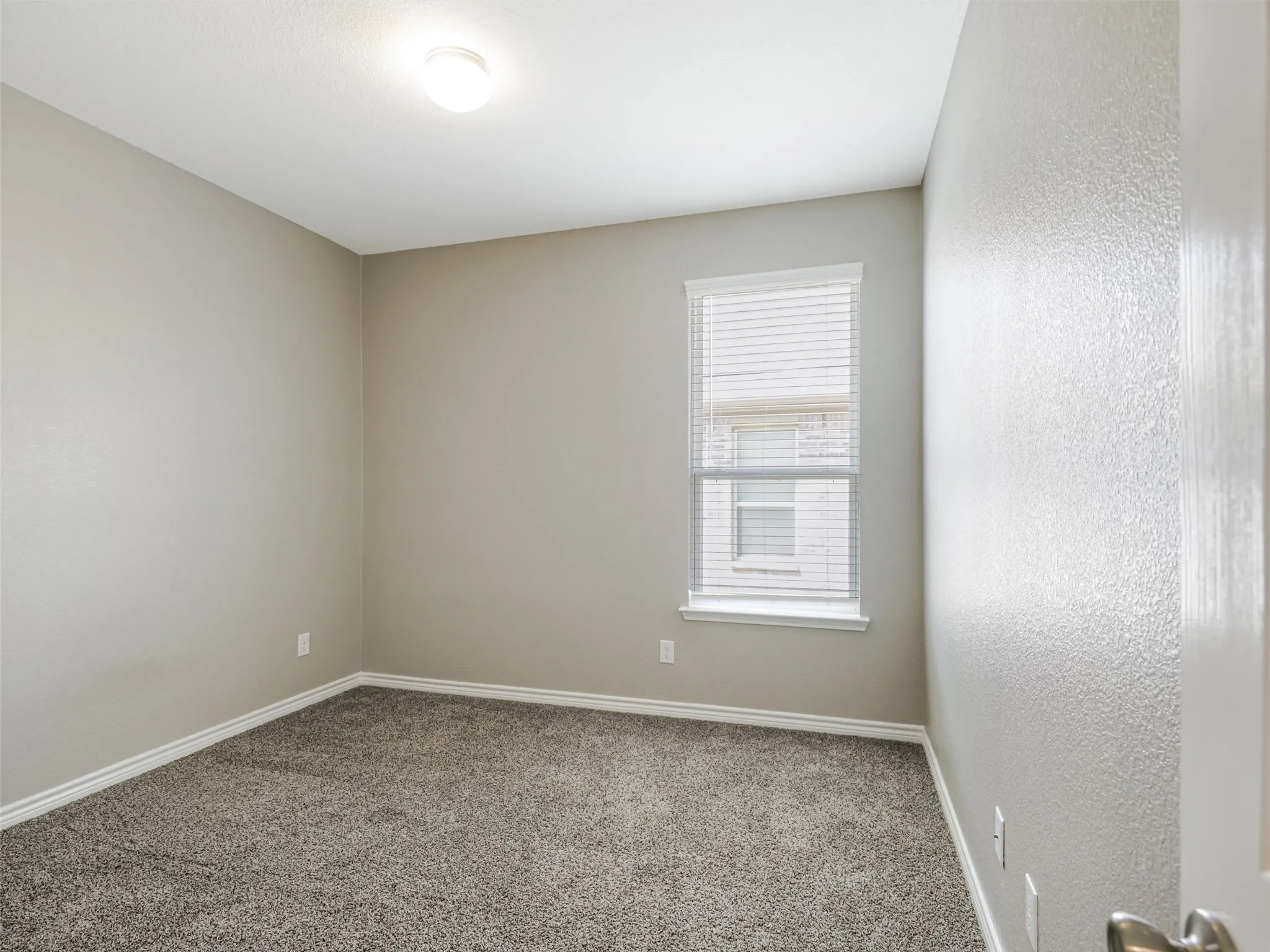 Versatile secondary bedroom offers neutral finishes, plush carpeting, and a window that brings in natural light.