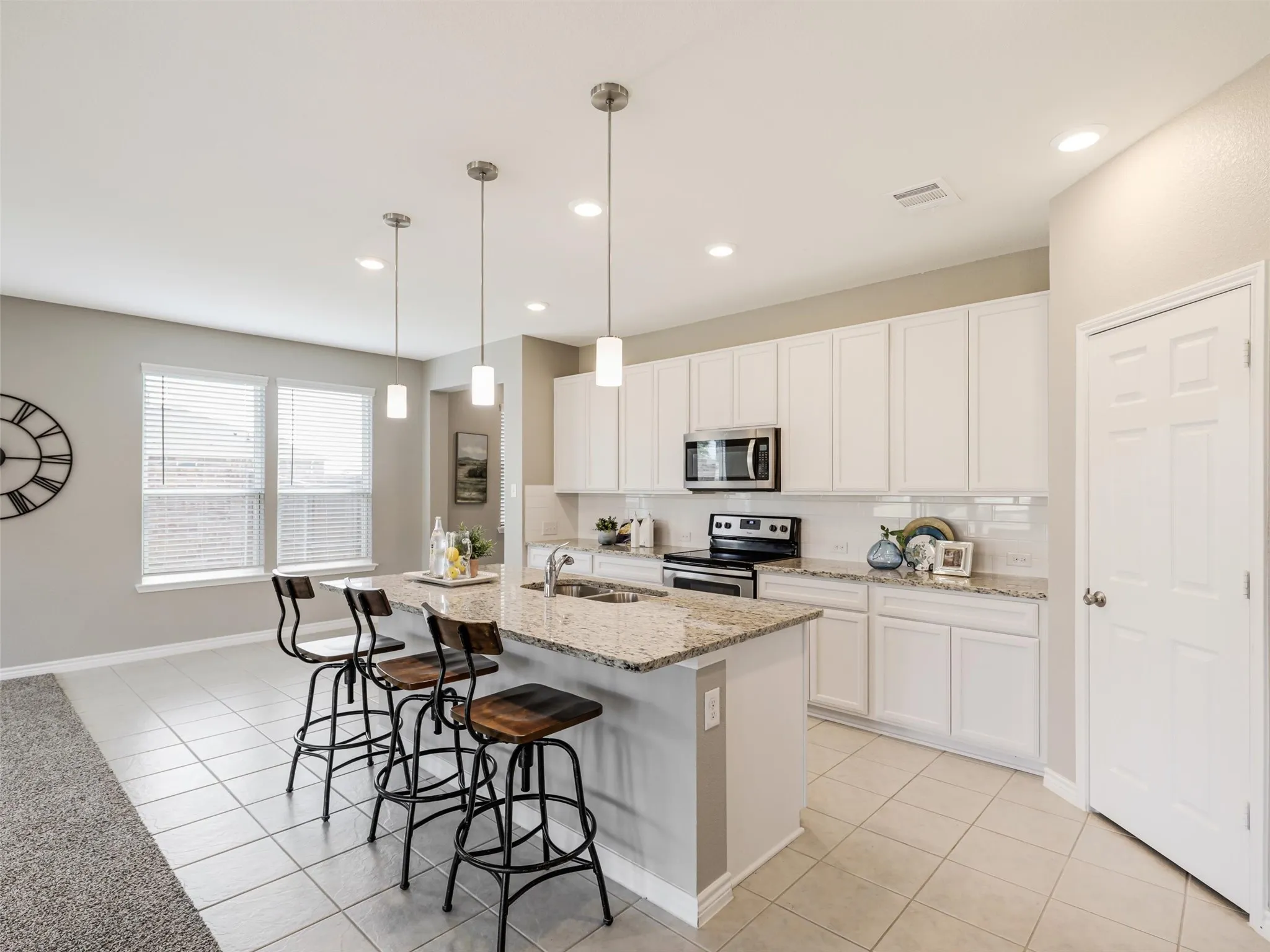 Light-filled kitchen showcasing an open layout, ample cabinetry and counter space, recessed lighting, pendant fixtures, and easy flow into the adjoining living area.