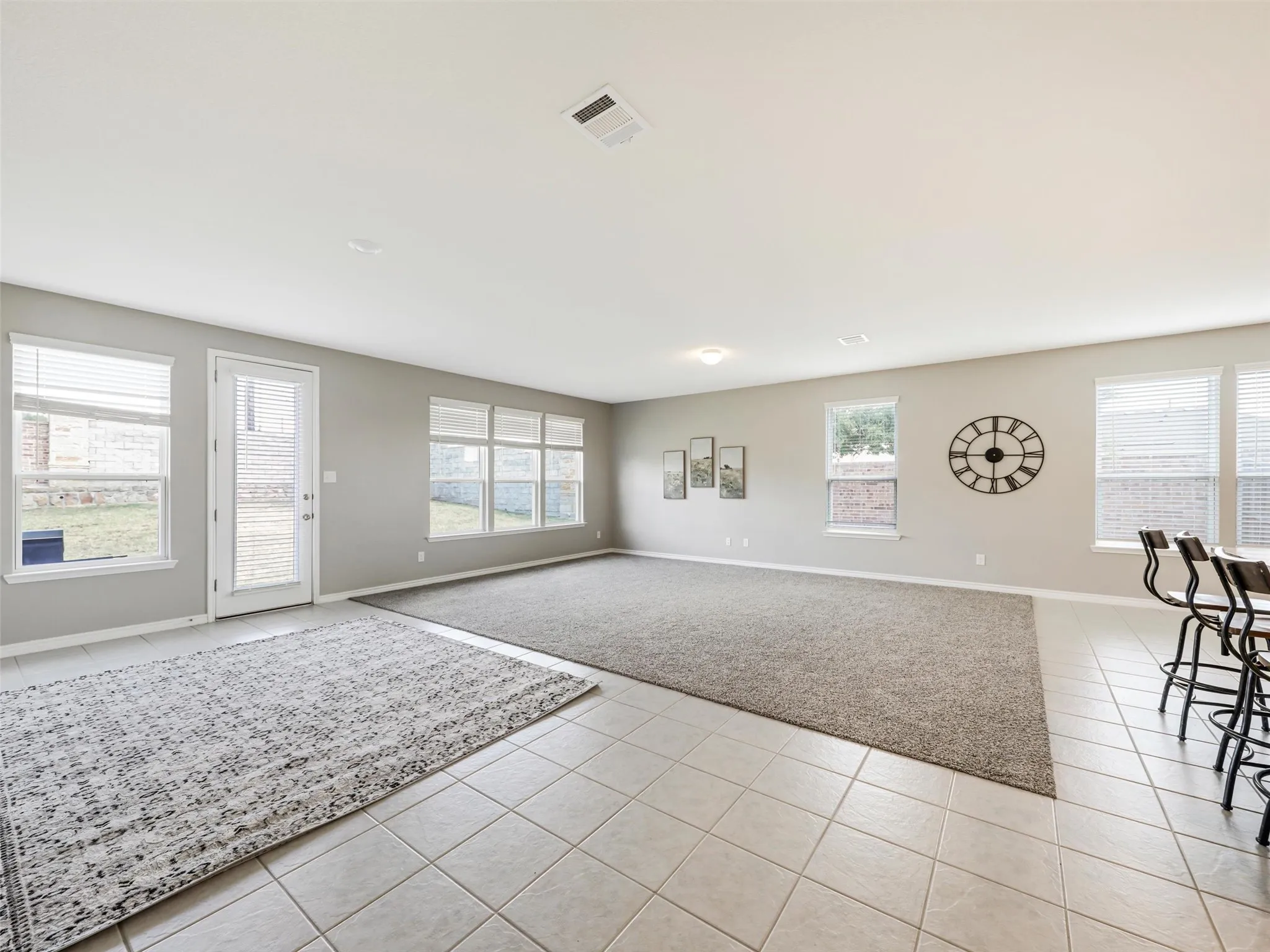 Bright and spacious main living area showcases an open layout, numerous windows, neutral finishes, and a comfortable flow between the kitchen, dining, and outdoor spaces.