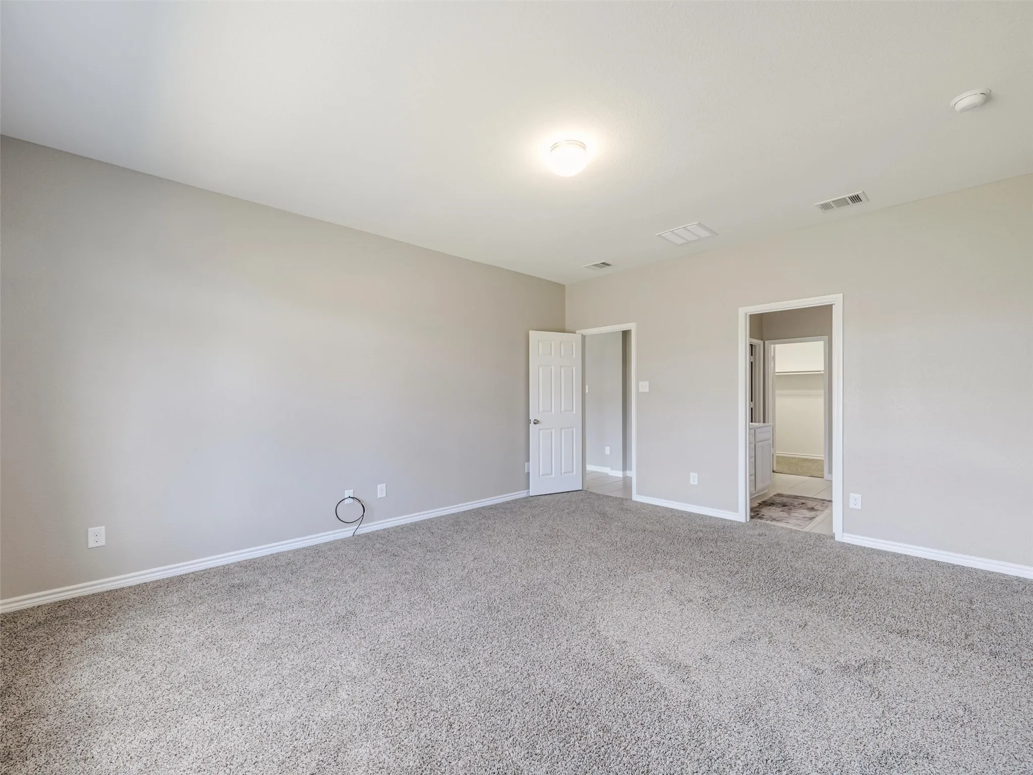 Another view of the primary bedroom highlights its impressive size and direct connection to the ensuite bathroom and walk-in closet.
