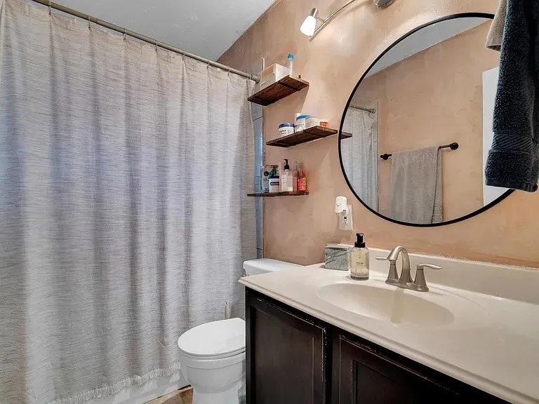 Modern bathroom featuring a dark wood vanity with white quartz countertop, polished chrome faucet, and integrated sink