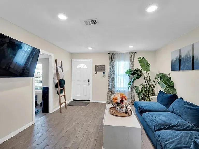 Recessed lighting, wood-finish flooring, white paneled entry door with arched lites, and large windows with privacy blinds