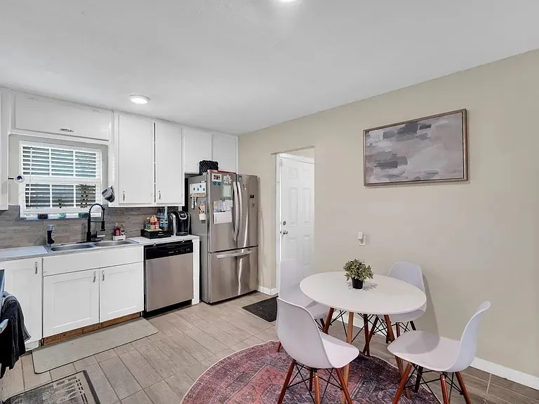 White cabinetry, stainless steel appliances, tile flooring, and a subway tile backsplash