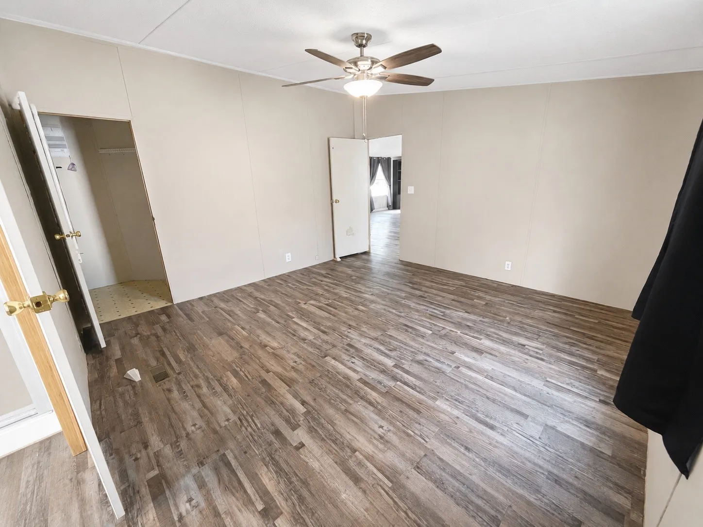 Wood-finish flooring throughout, light-toned walls, and a ceiling fan with integrated lighting