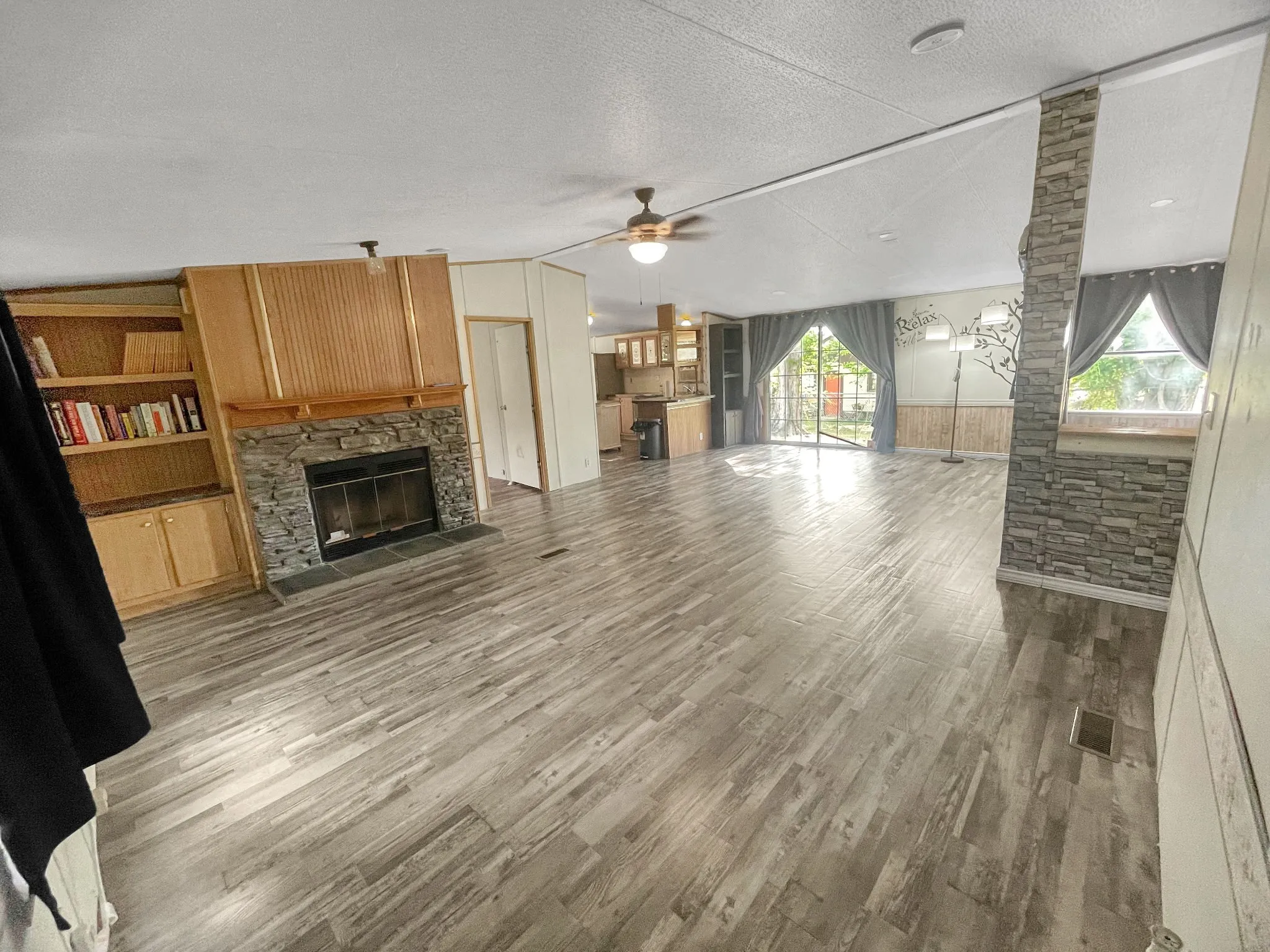 Expansive living area featuring wood-finish flooring, built-in shelving, and sliding glass doors