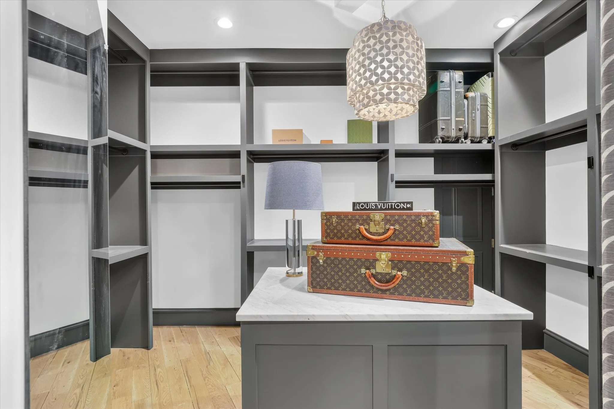 Custom-fitted primary closet offers extensive storage with a center island and thoughtfully designed built-ins.