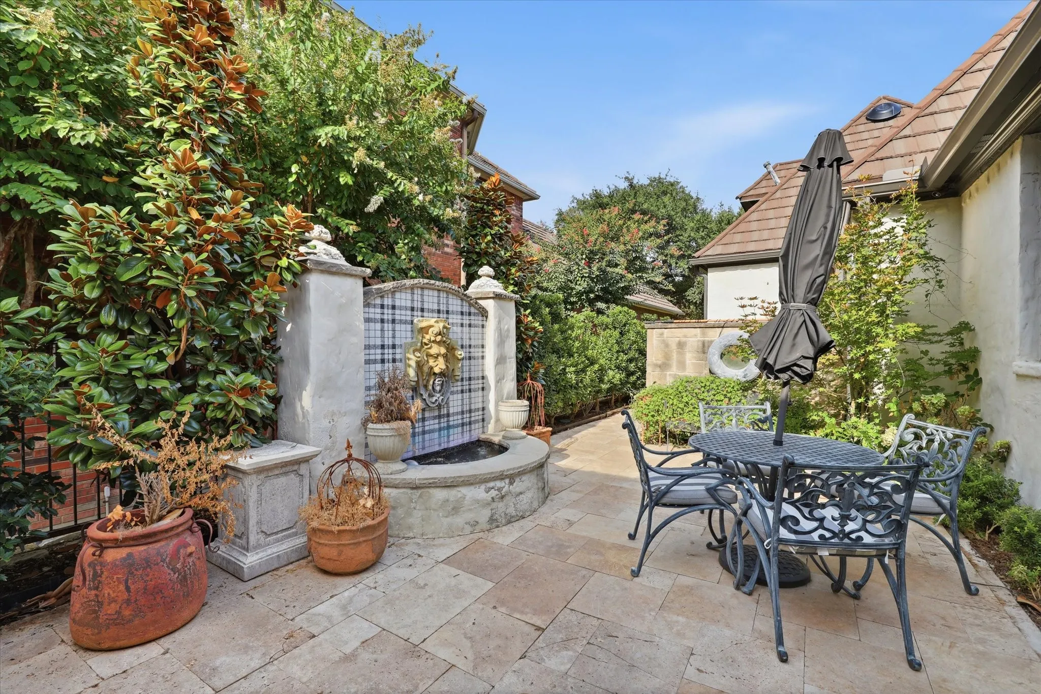 An intimate garden terrace tucked among mature landscaping offers a charming additional space for outdoor dining.