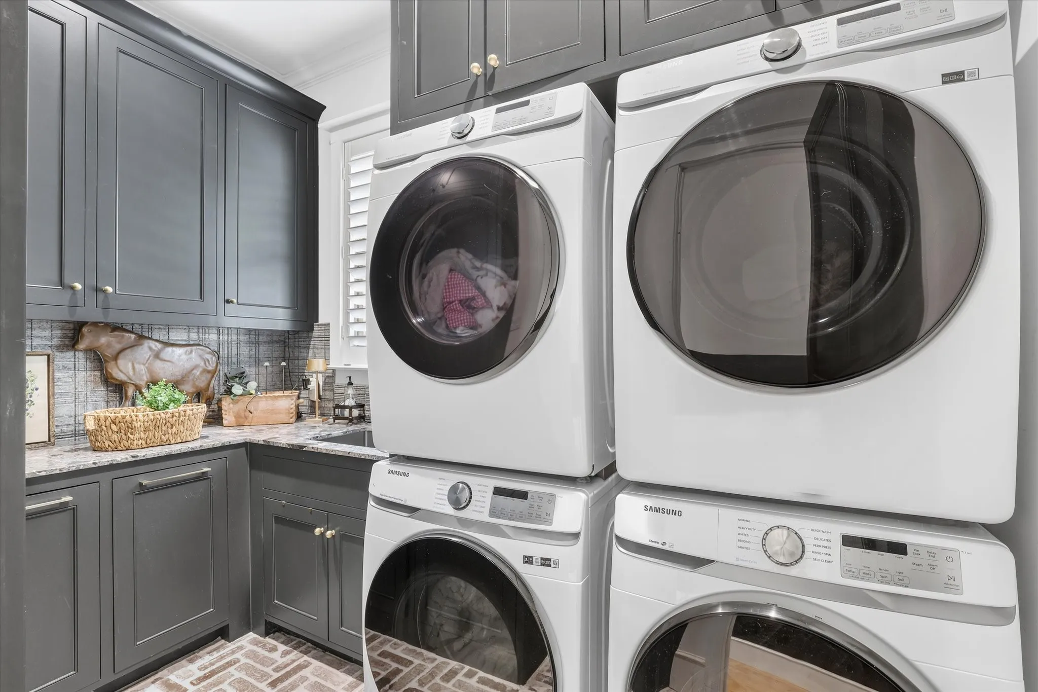 Beautifully finished utility room with extensive cabinetry and space for dual stacked washer and dryer sets.