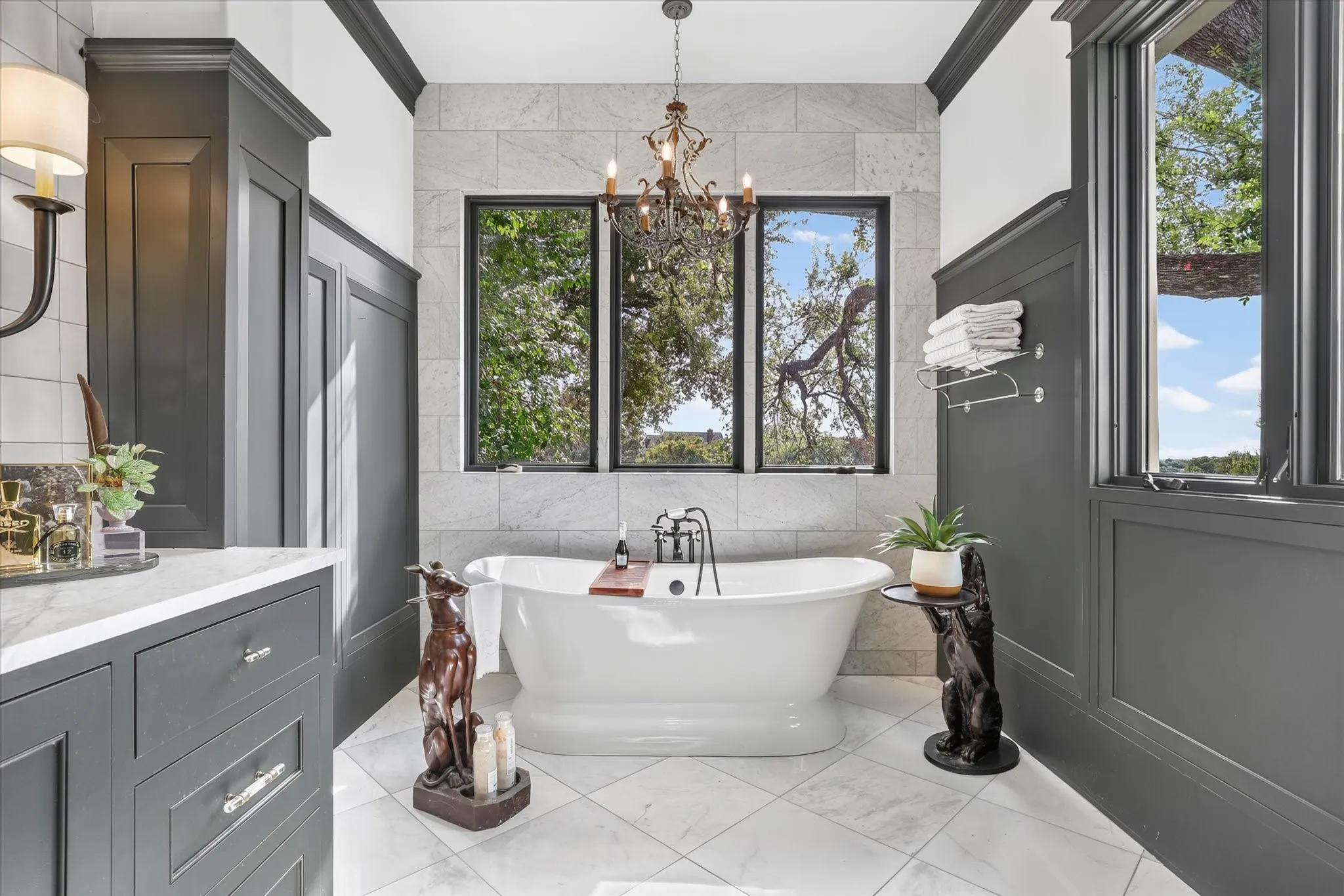 Freestanding soaking tub creates a luxurious focal point beneath windows overlooking the private grounds.