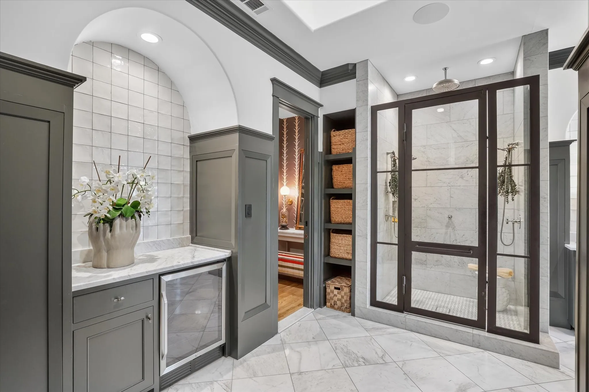 Dramatic glass-enclosed shower and custom cabinetry elevate the primary bath with boutique-hotel style.