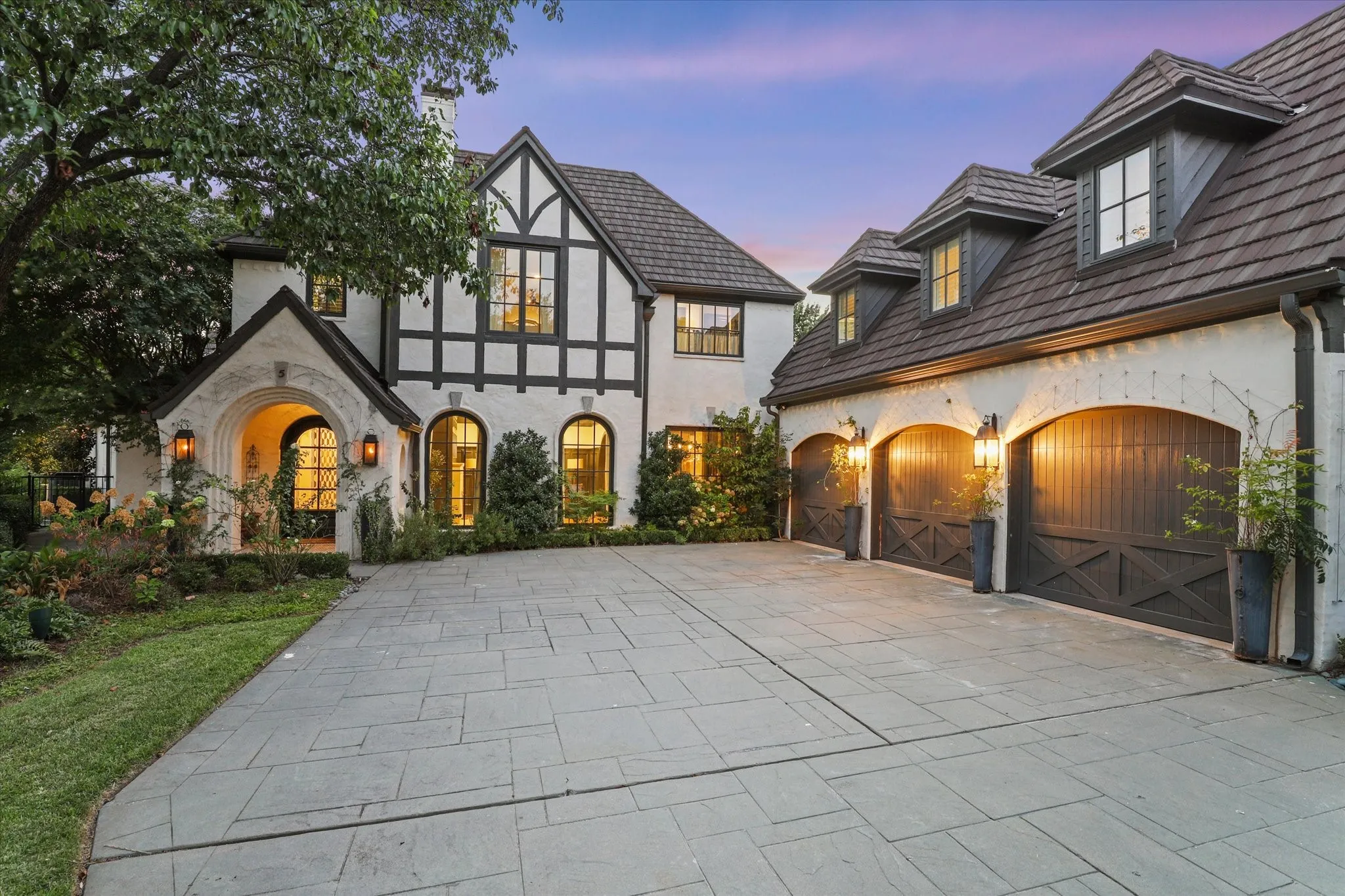 Tudor-inspired architecture takes on a dramatic presence at twilight with warm architectural lighting.