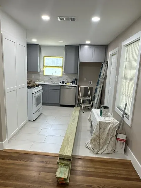 Recessed lighting, wood-finish flooring, white flat-panel cabinetry, gray shaker-style cabinetry, and light-toned tile flooring