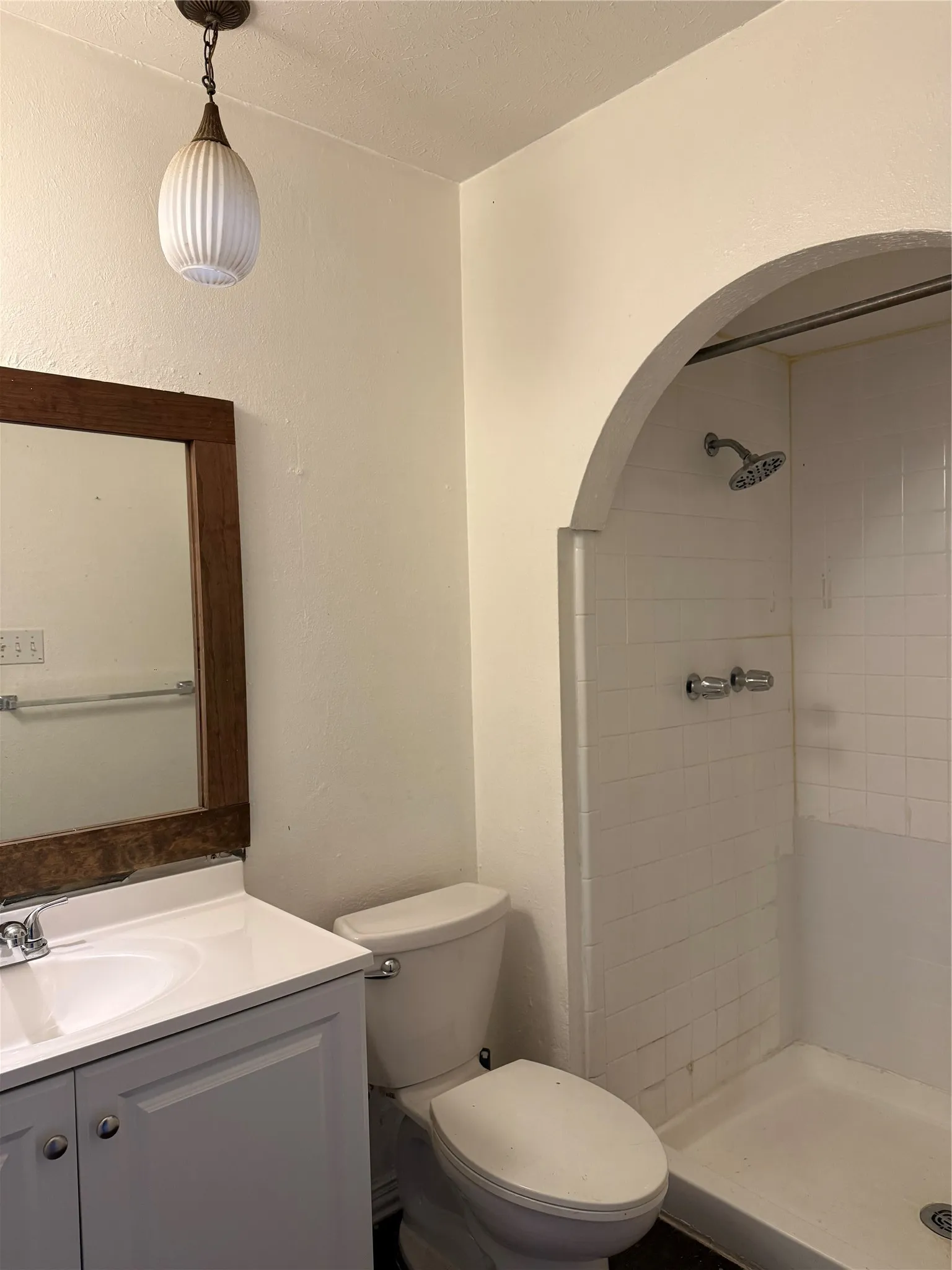 Recessed shower area with arched entry, white tile surround, and chrome fixtures