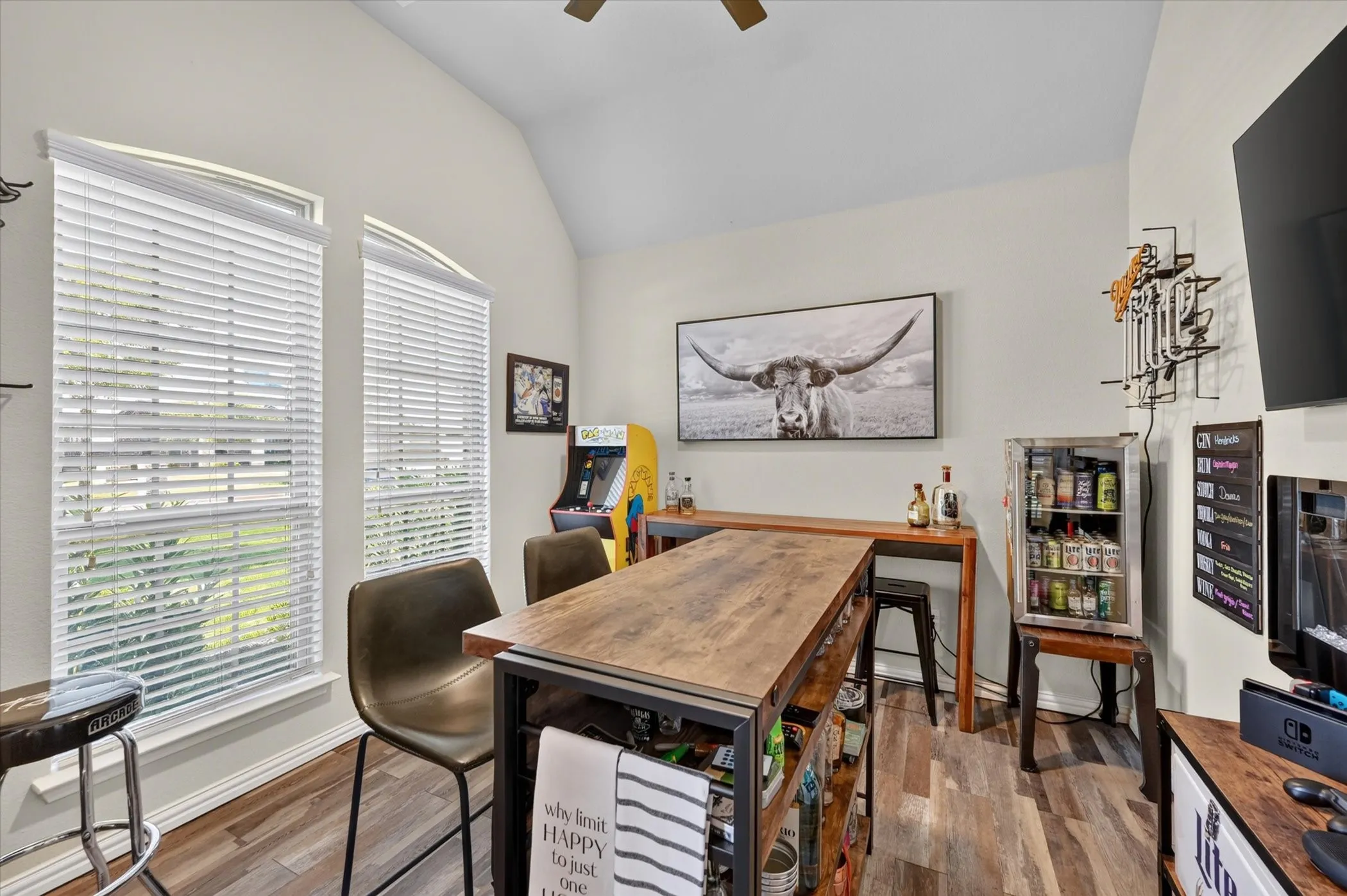 Vaulted ceiling with a ceiling fan, wood-finish flooring, and arched windows