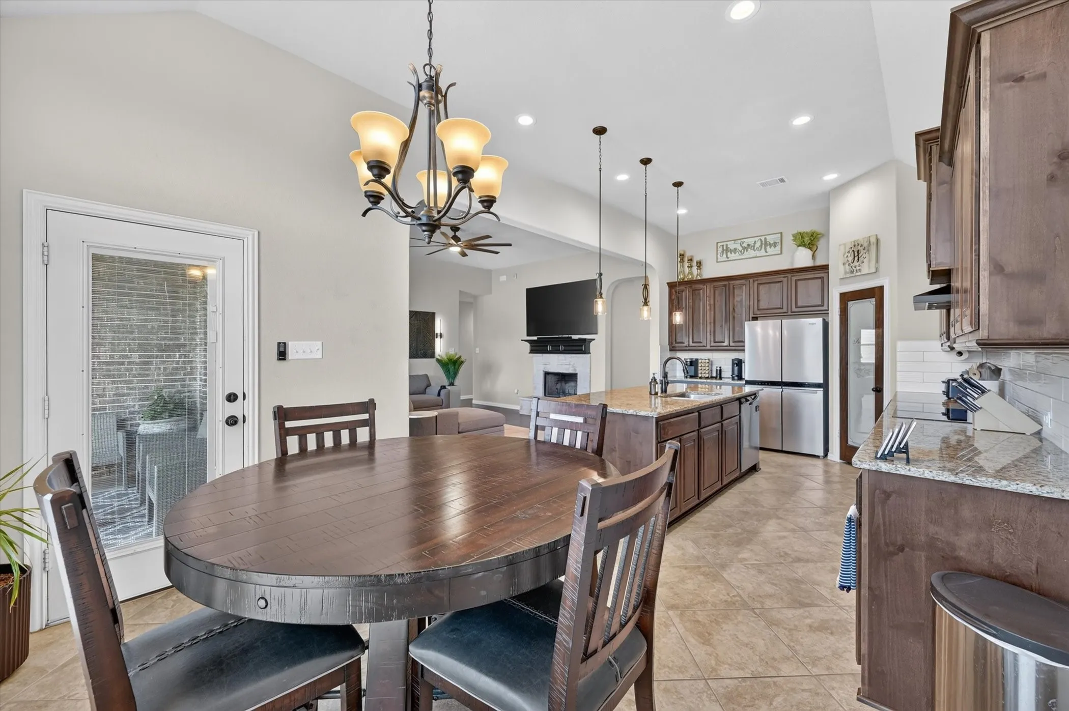 Vaulted ceilings with recessed lighting, granite countertops, tile flooring, stainless steel appliances, and dark wood cabinetry